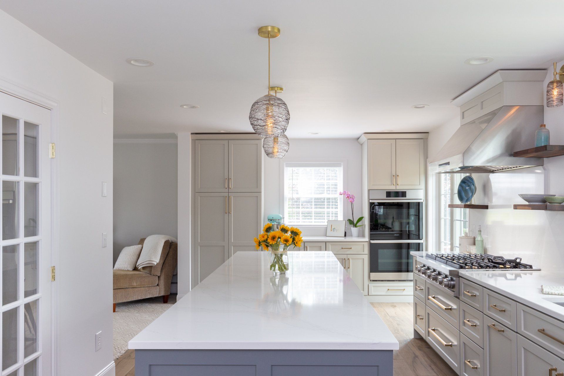 Bright modern kitchen with white island, stainless appliances, and a vase of yellow flowers