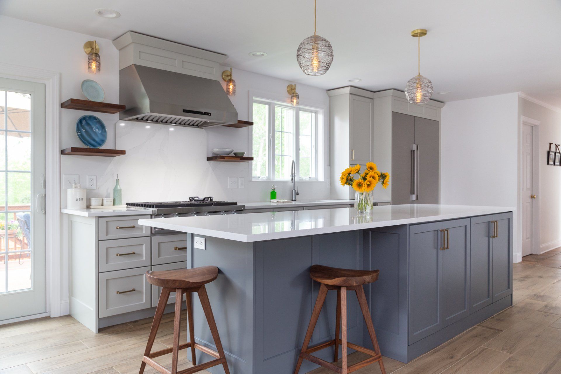 Bright modern kitchen with gray cabinets, large island, stools, and pendant lights
