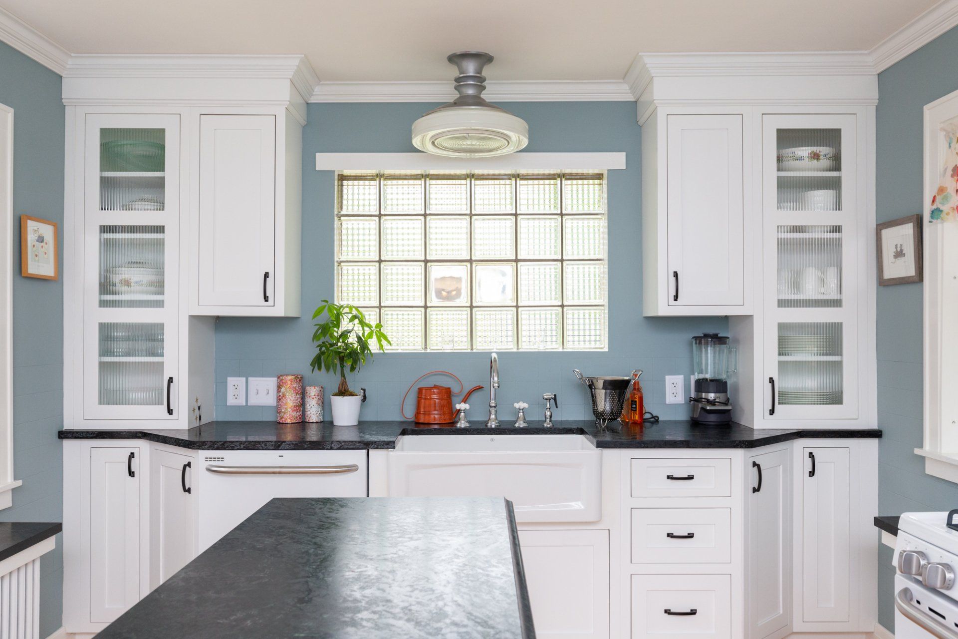 Bright kitchen with white cabinets, blue backsplash, and a large window over the sink.