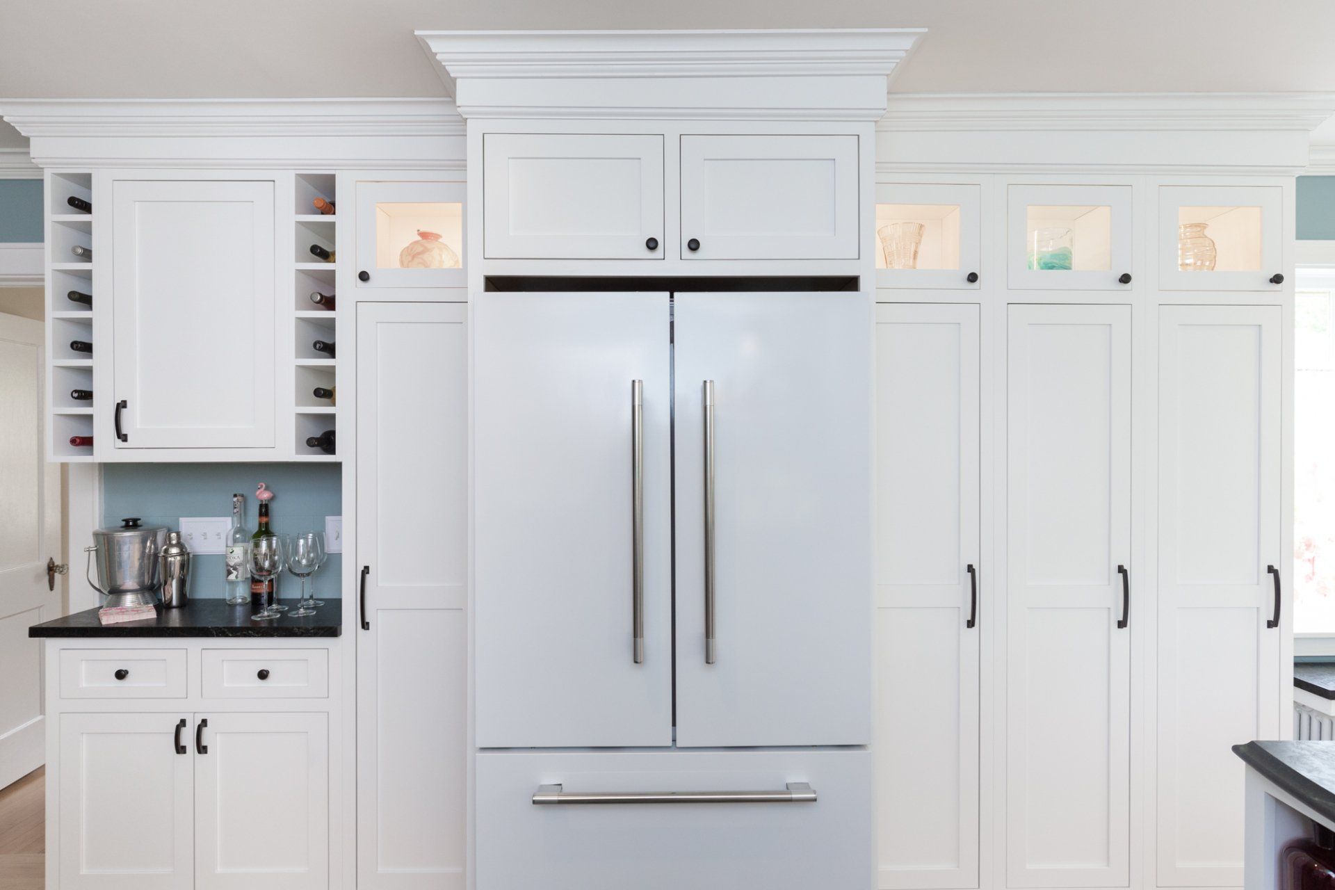 White kitchen with built-in stainless steel refrigerator, cabinets, and black countertop