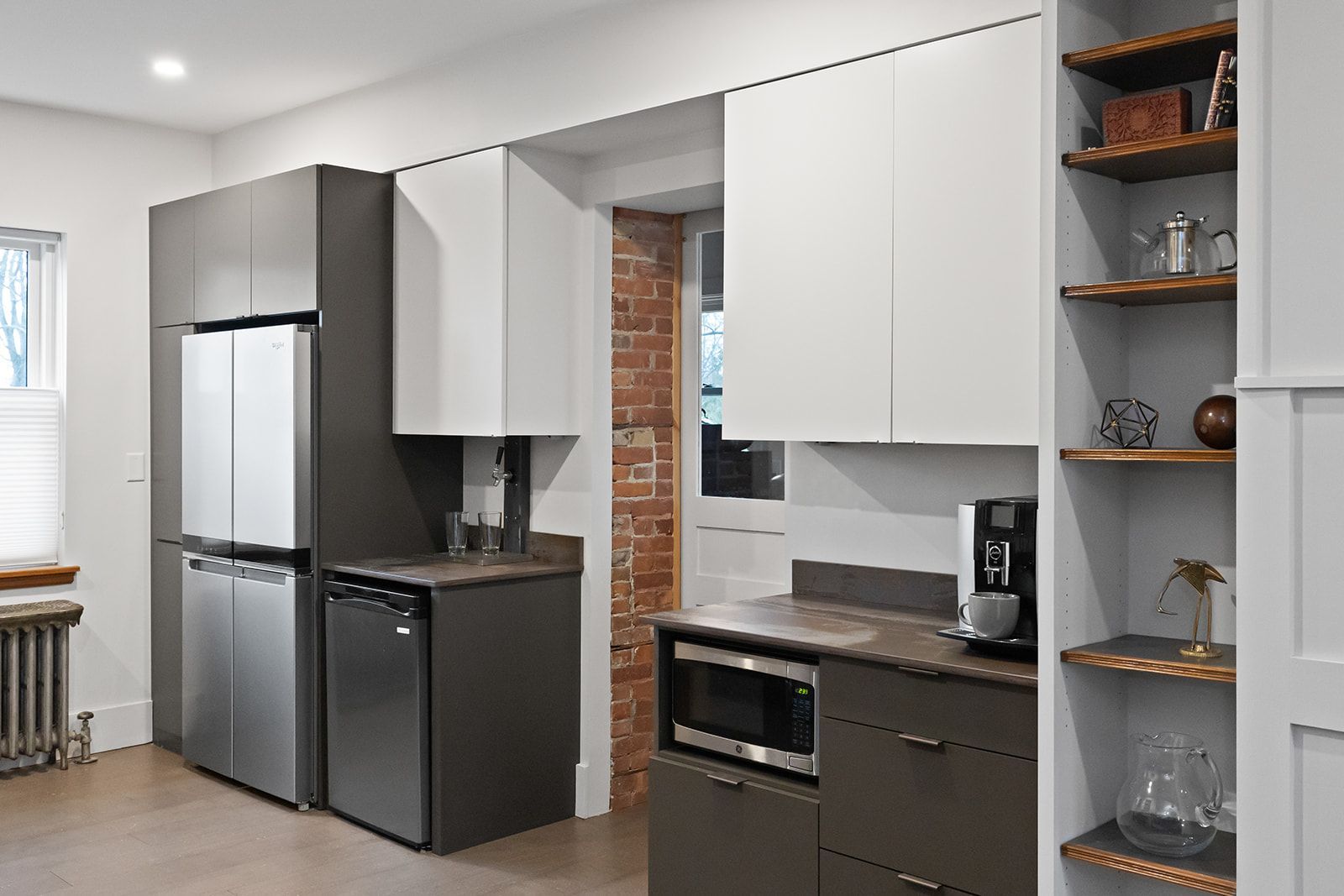 Modern kitchen with white cabinets, dark countertops, stainless fridge, and open shelving
