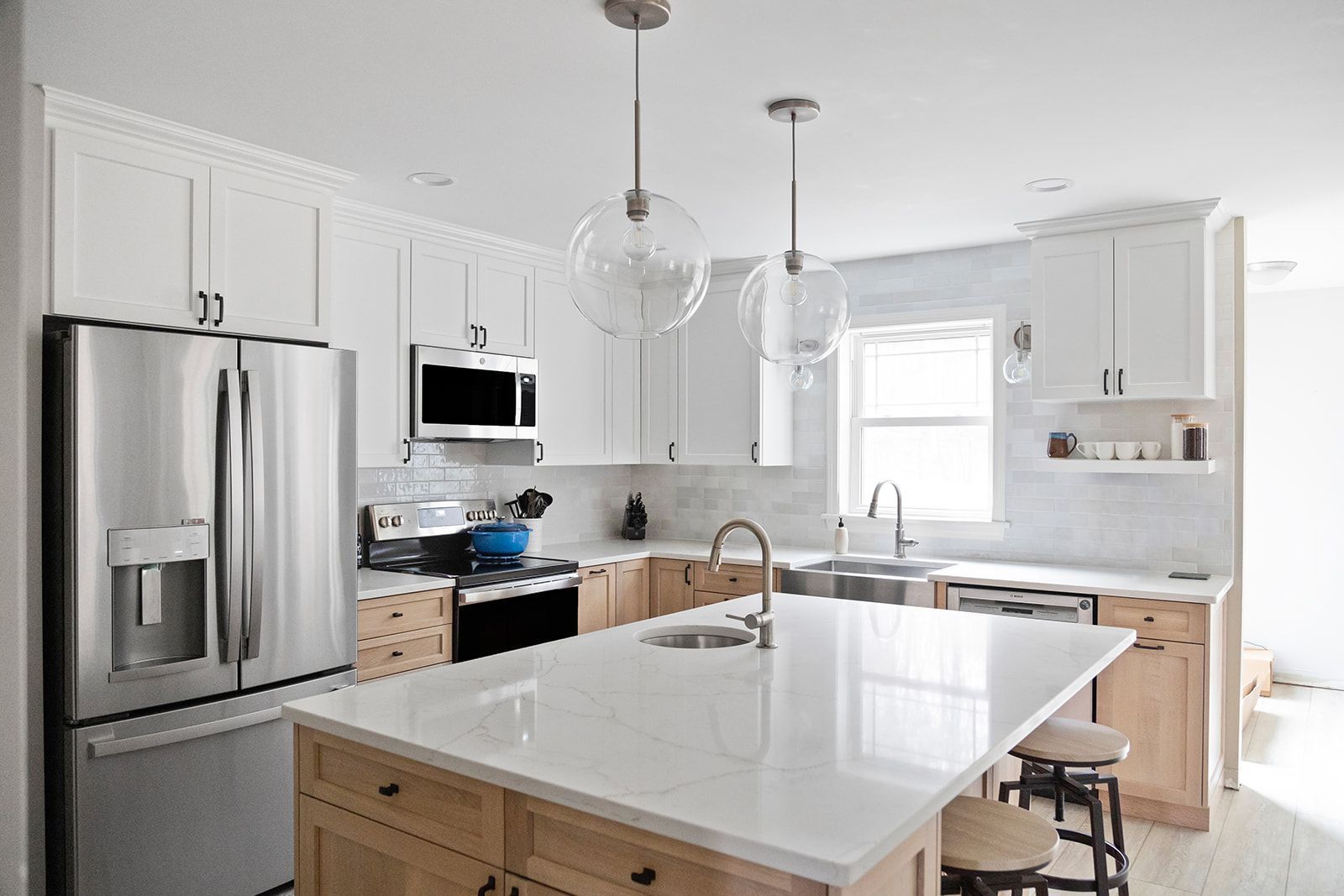Bright modern kitchen with white cabinets, stainless steel appliances, and a large island