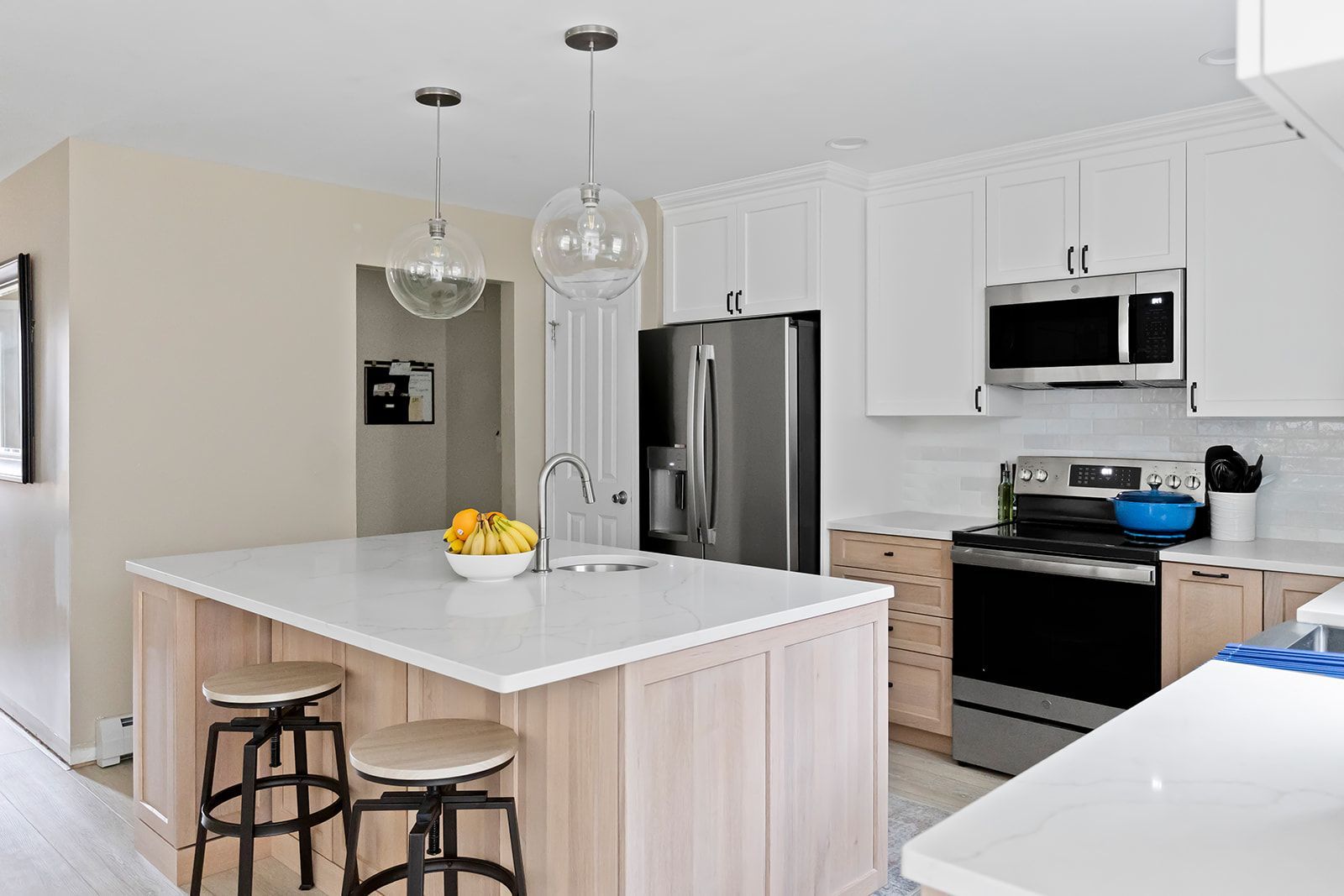 Modern white kitchen with island, stainless steel appliances, and pendant lights