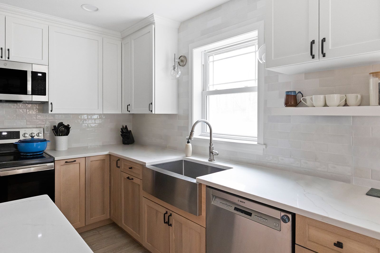 Modern white and wood kitchen with stainless steel appliances and a large sink by the window