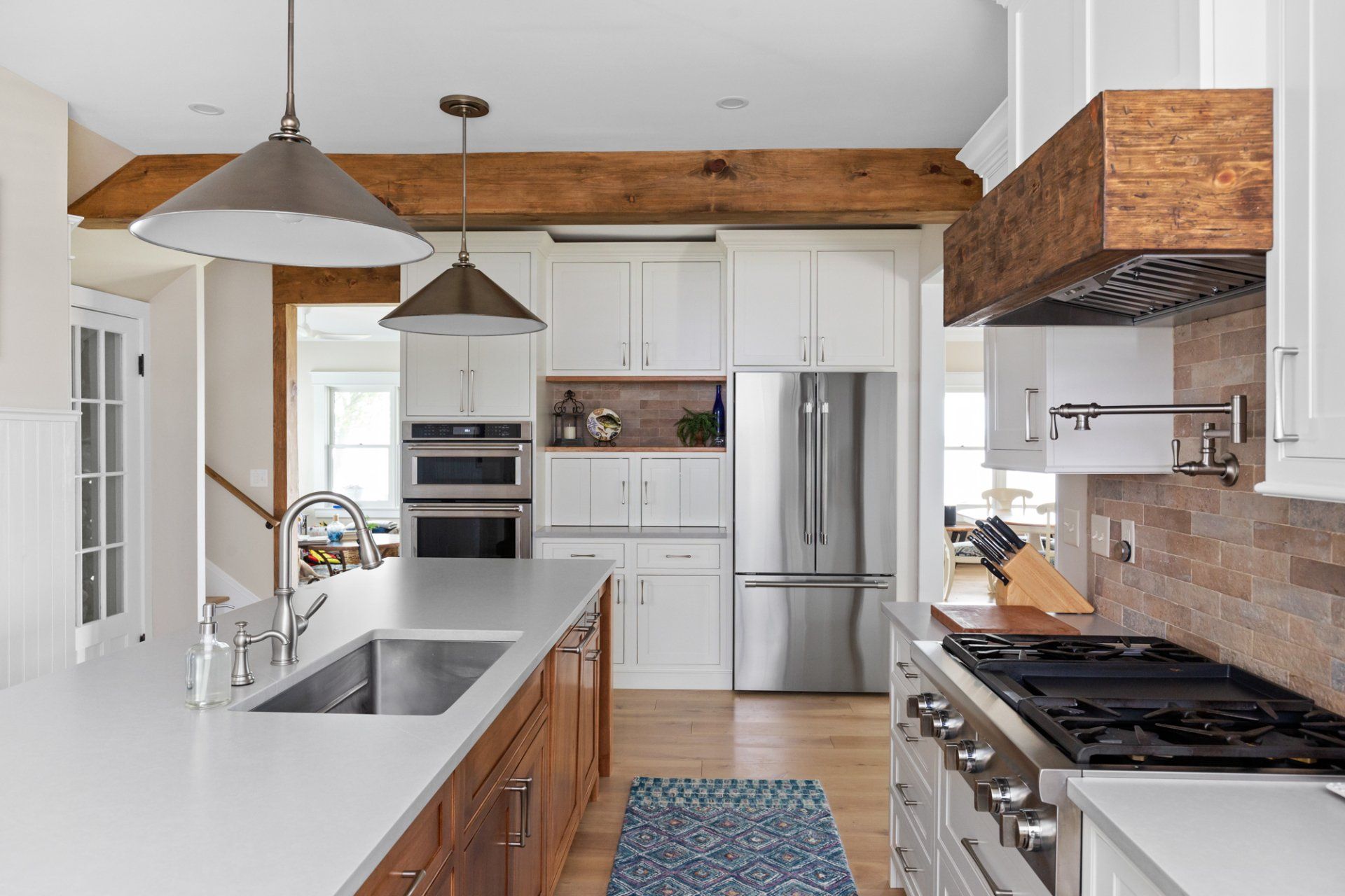 Bright modern kitchen with white cabinets, wood accents, stainless steel appliances, and a large island.