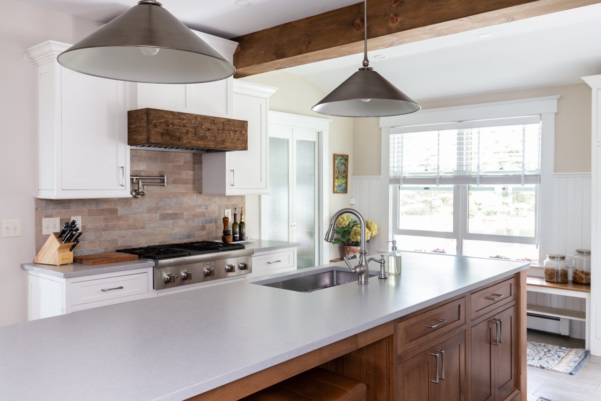 Bright modern kitchen with white cabinets, wood island, stainless stove, and large pendant lights