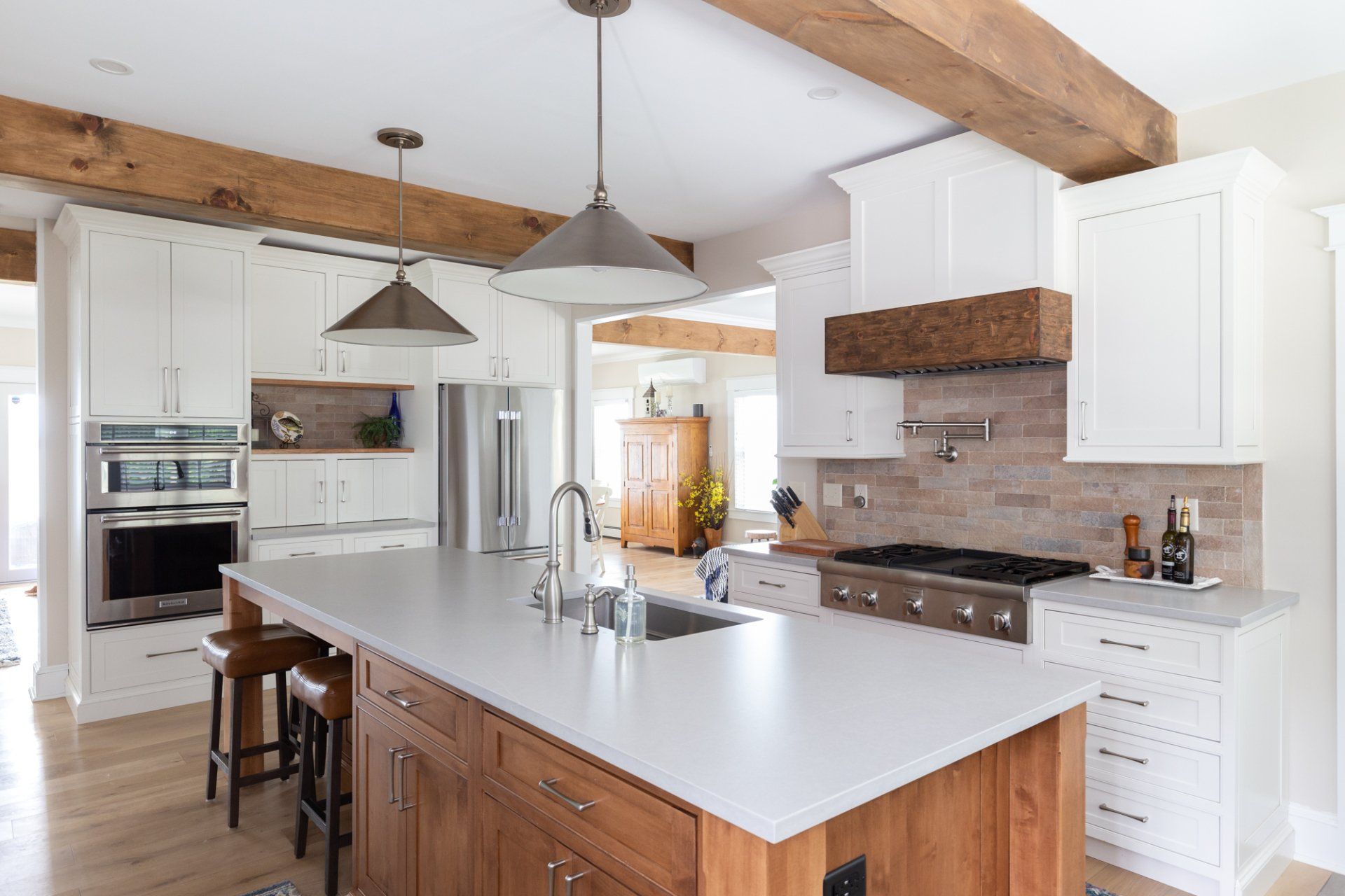 Bright modern kitchen with white cabinets, wood beams, and a large island with bar stools