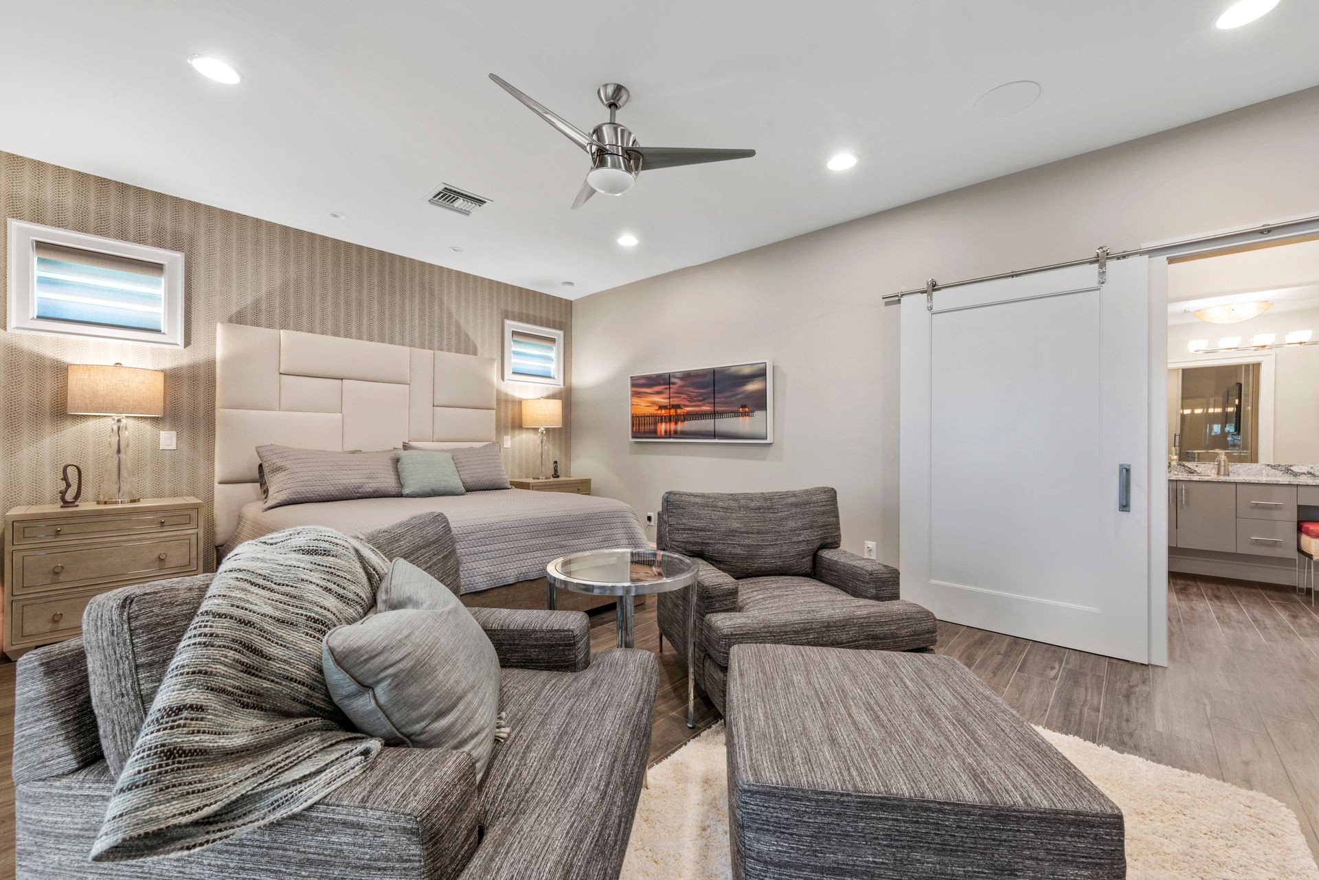 A bedroom with a large bed , chairs , and a ceiling fan.