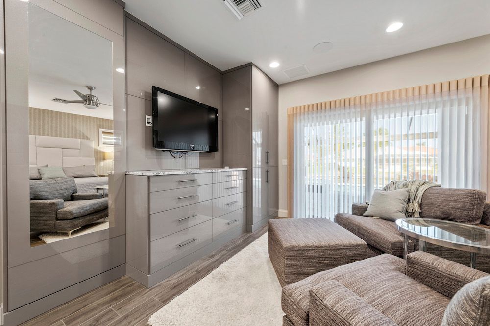 A living room with a couch , chairs , ottoman and television.