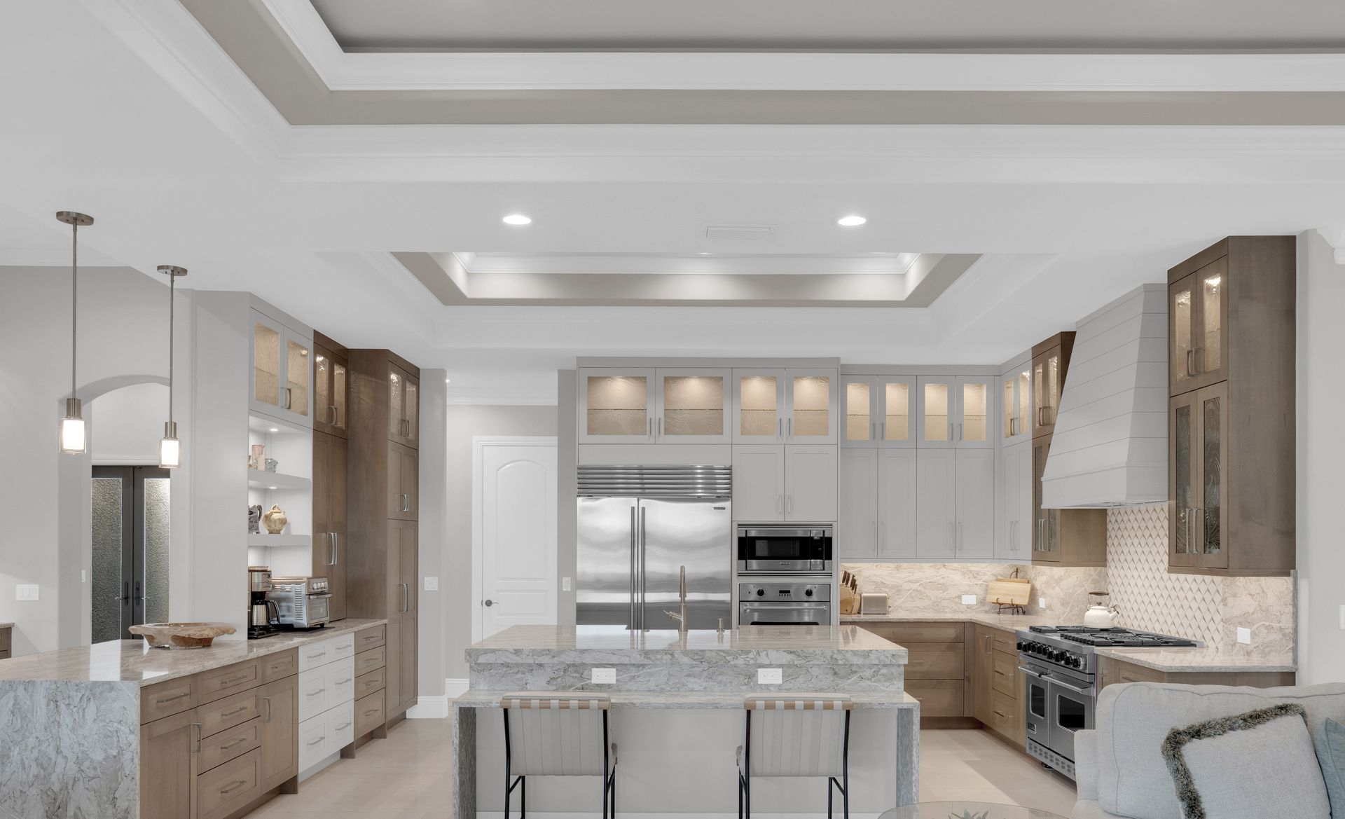 Modern kitchen with gray and brown cabinets, stainless steel appliances, and a large island.