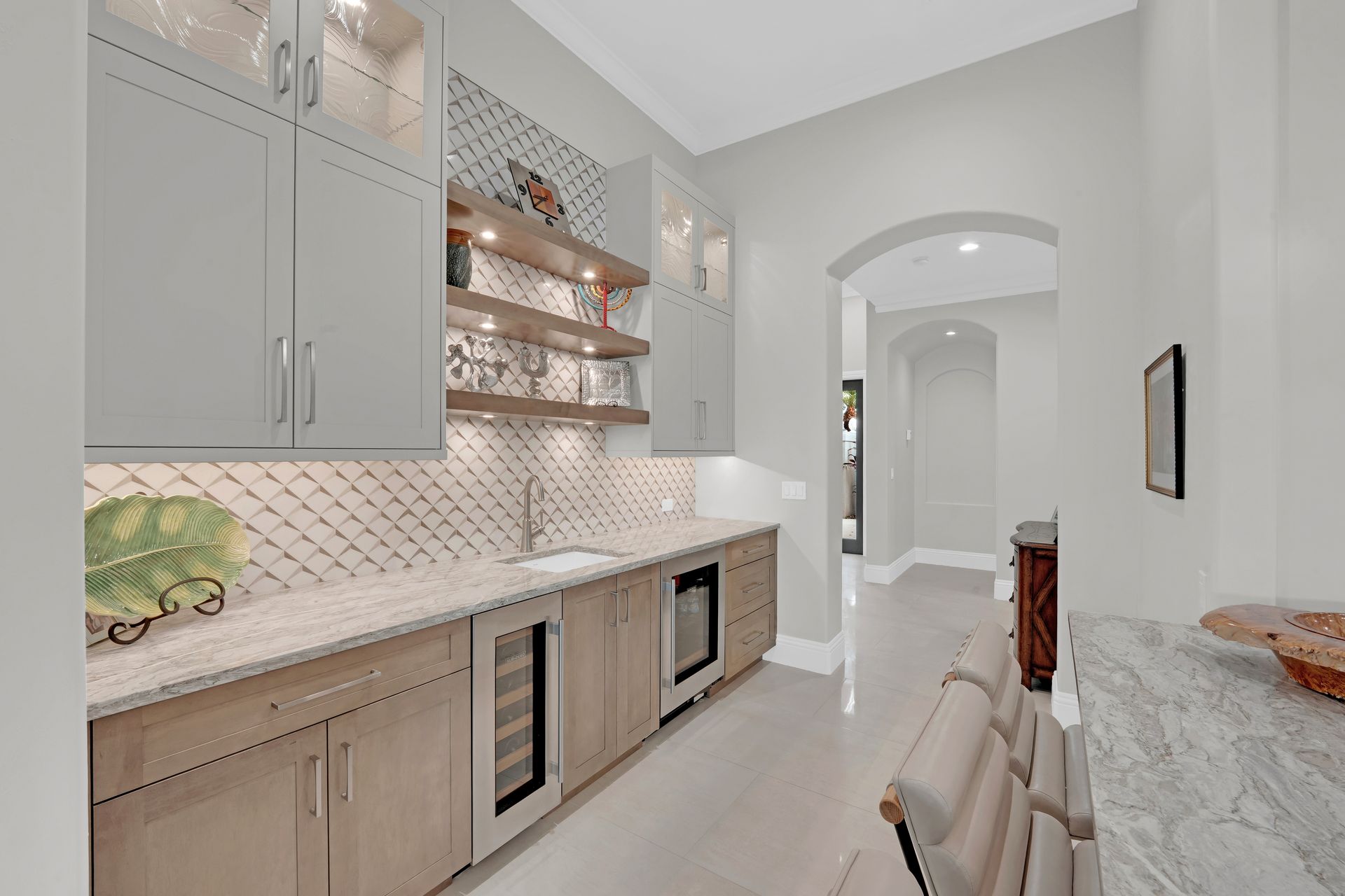 Bar area with cabinets, counter, and sink; arched doorway leads to a hallway.