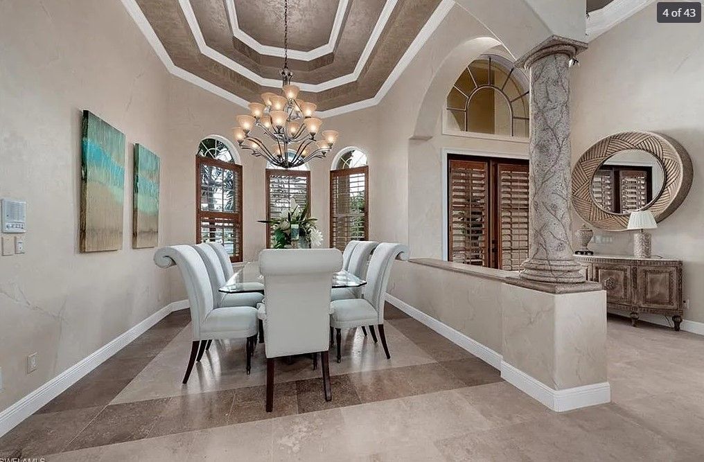 Elegant dining room with chandelier, arched windows, and light blue chairs.