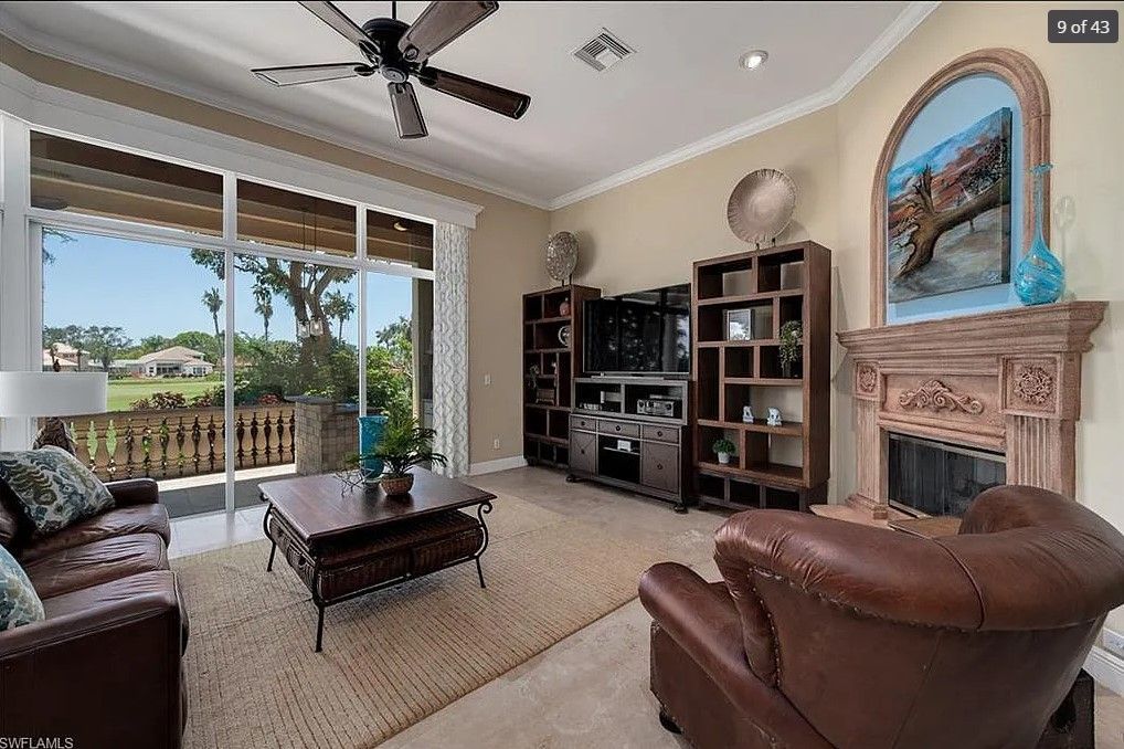 Living room with leather furniture, large windows, fireplace, and entertainment center.