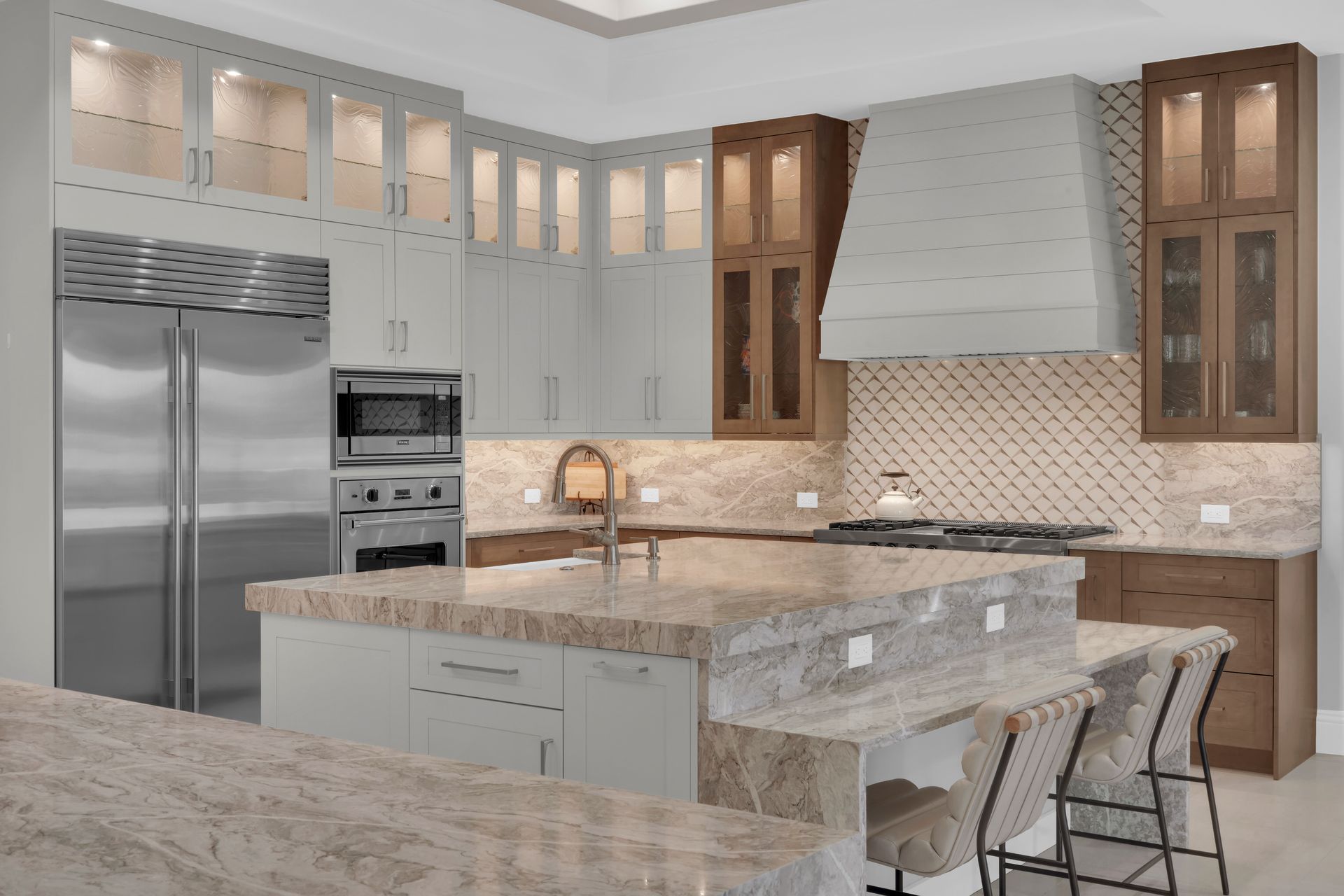 Modern kitchen with island, stainless steel appliances, light gray and wood cabinets, and granite countertops.