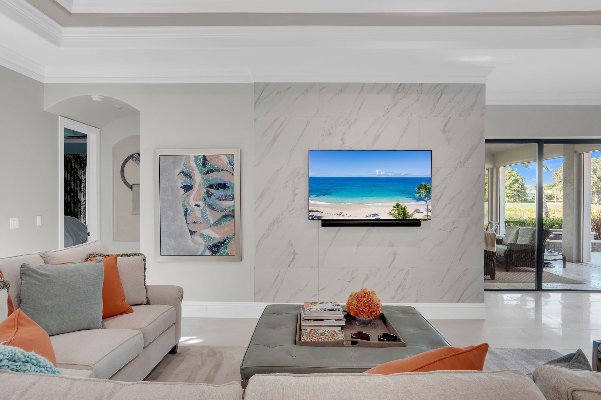 Living room with a marble accent wall, TV, art, and a light-colored couch.