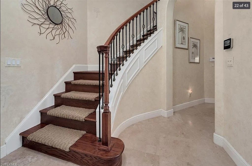 Staircase with wooden steps and railing, beige carpet, decorative mirror on wall.