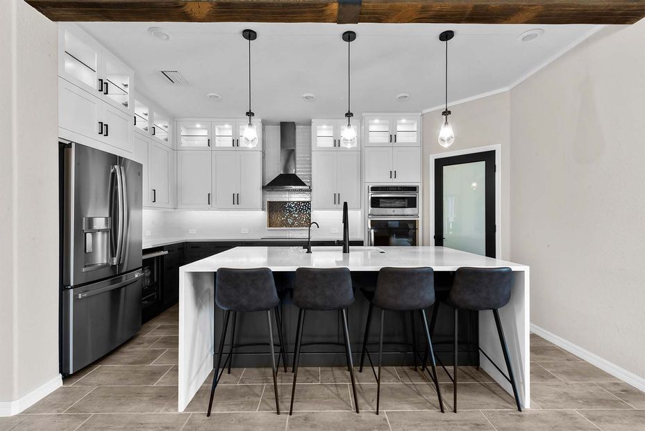 A kitchen with stainless steel appliances , white cabinets , and a large island.