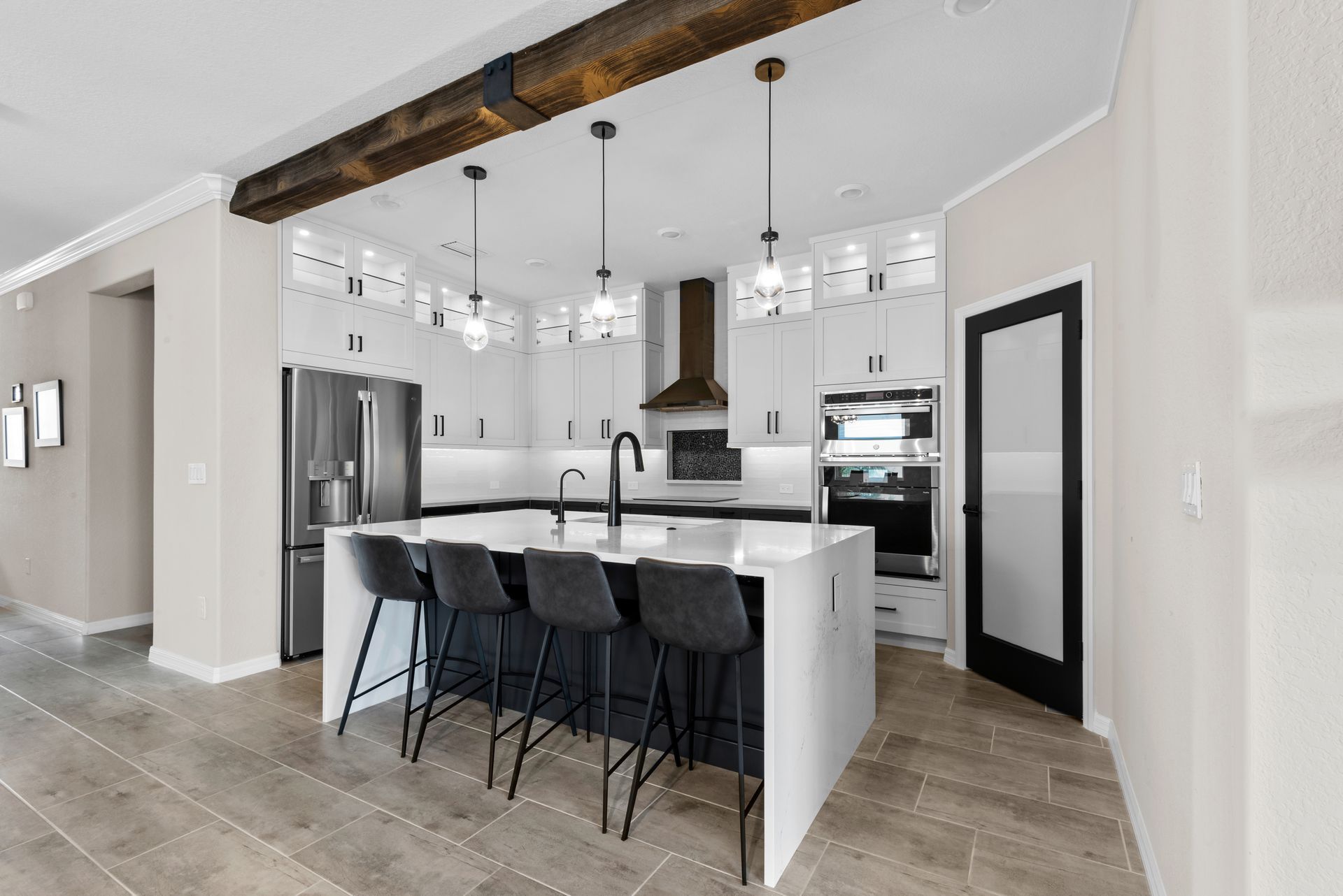 Modern kitchen with white cabinets, dark island with seating, stainless steel appliances, and dark accents.