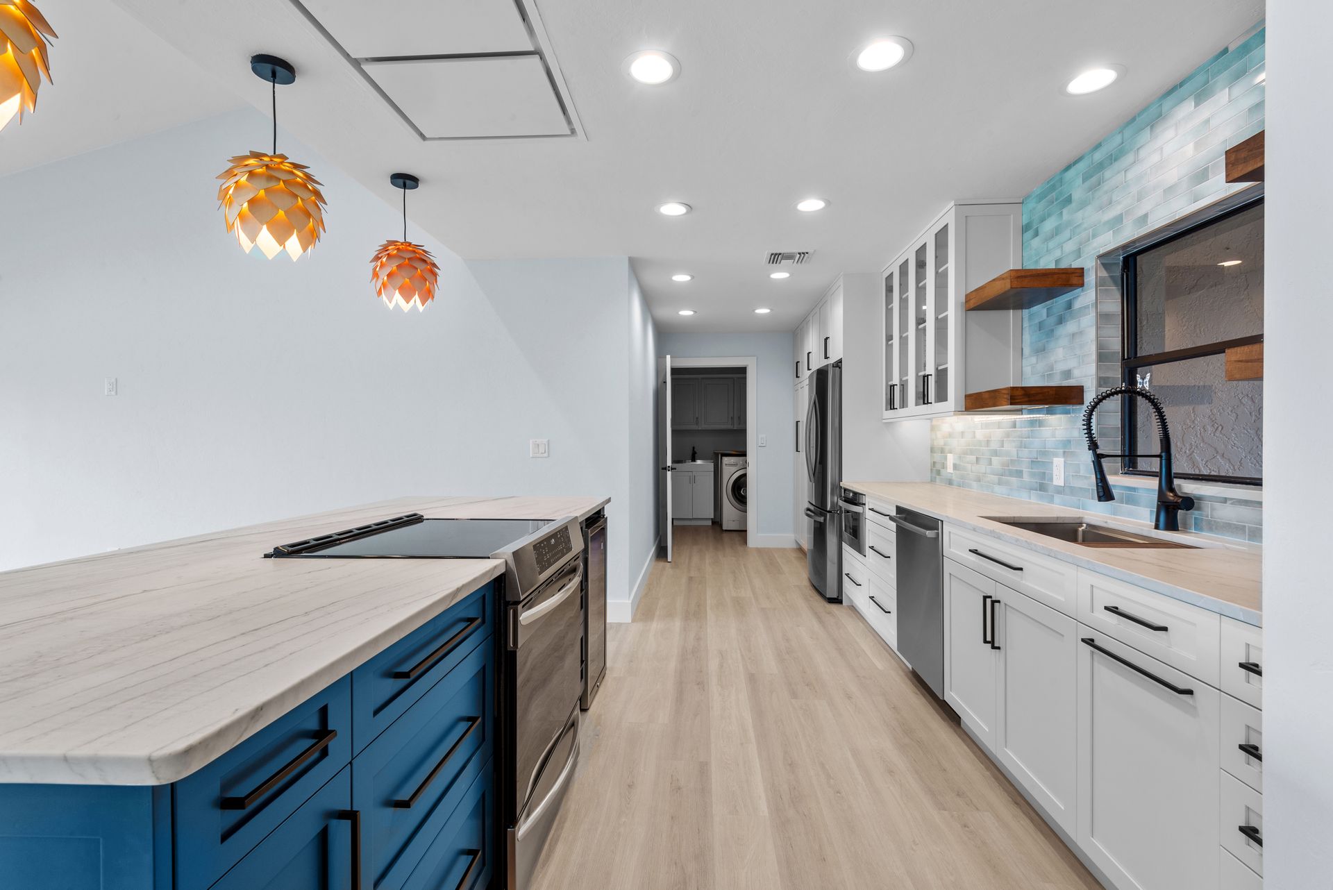 Modern kitchen with blue island and white cabinets. Wooden shelves, stainless steel appliances, and a turquoise backsplash.