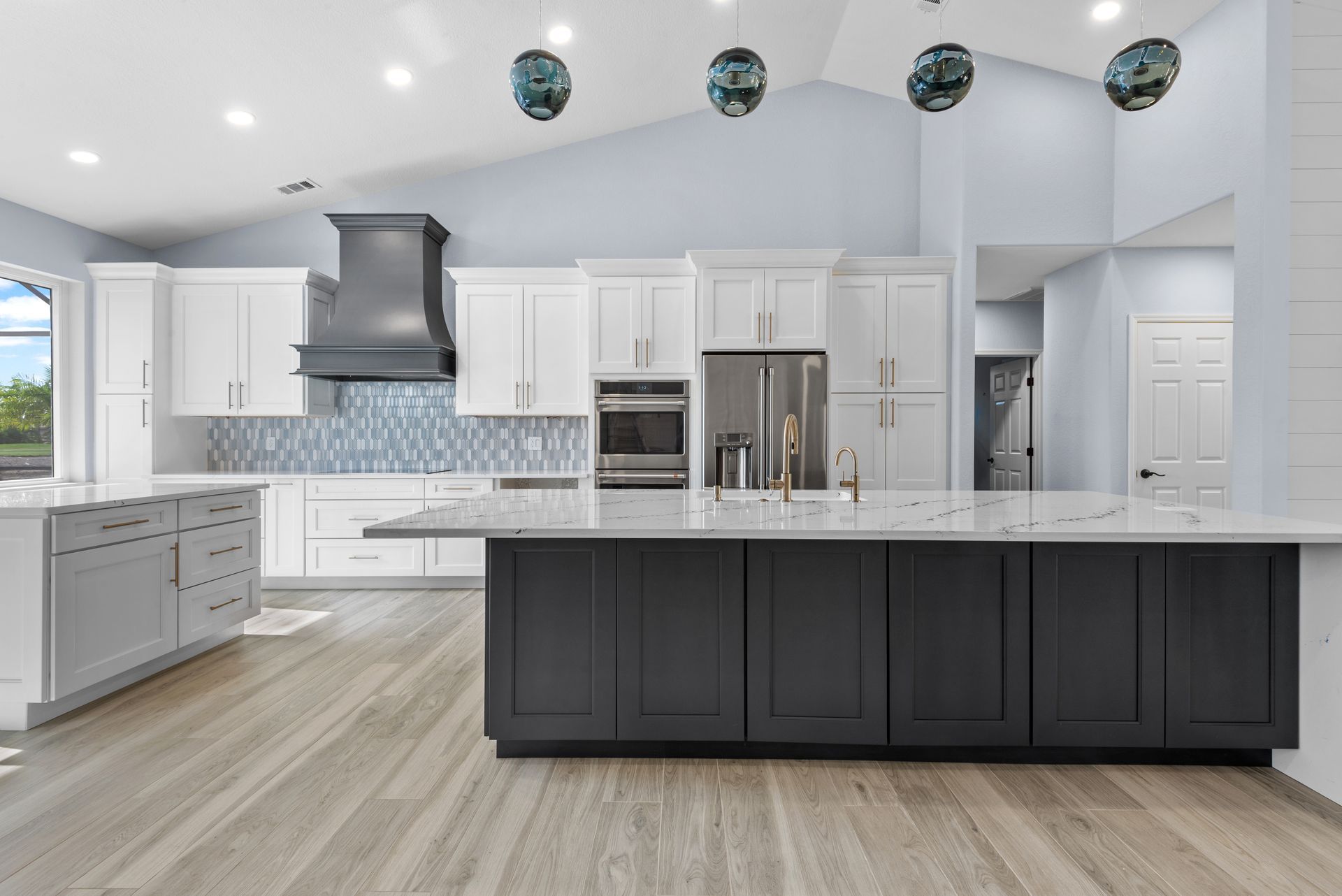 Modern kitchen with white and gray cabinets, large island, and wood floor.