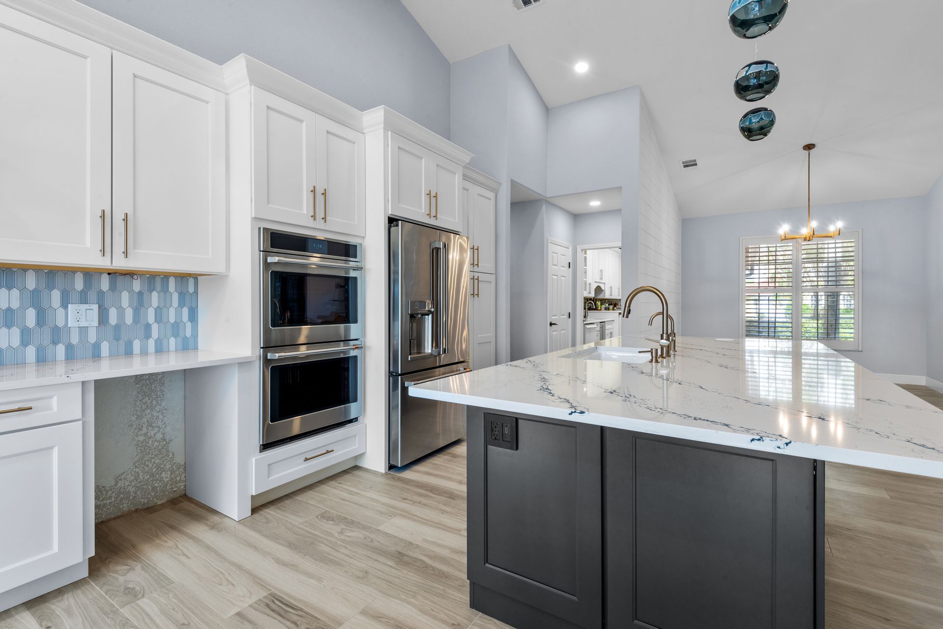 Modern kitchen with white cabinets, stainless steel appliances, and a dark island with white countertops.
