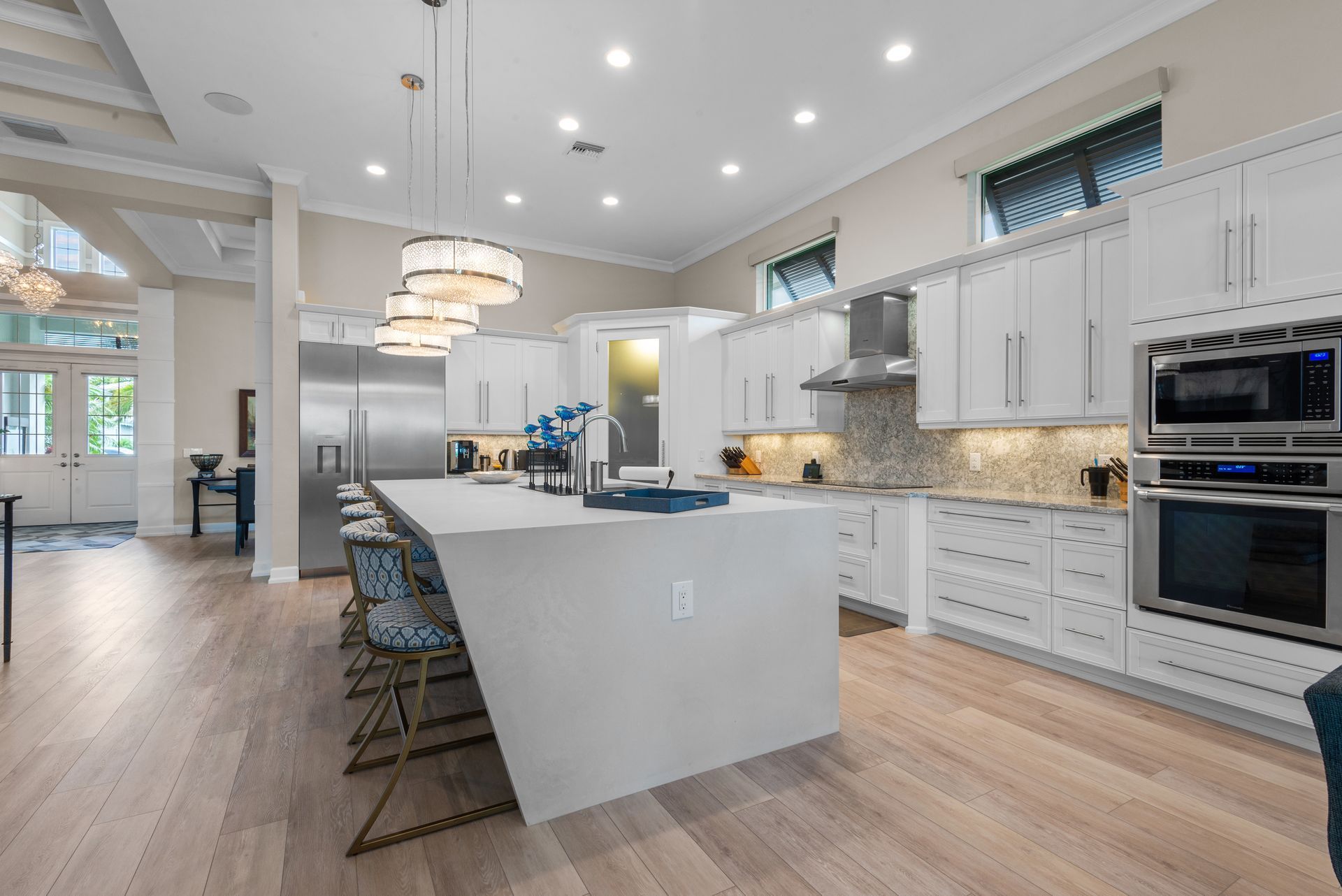 Modern white kitchen with island, stainless steel appliances, and wood flooring.