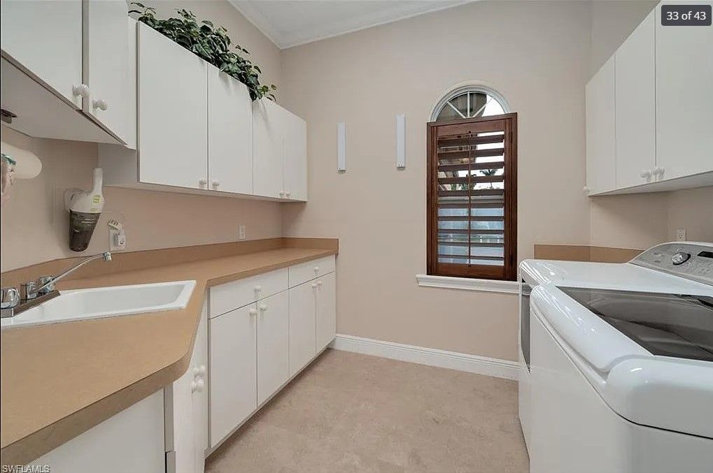 Laundry room with white cabinets, beige countertops, and a washing machine.