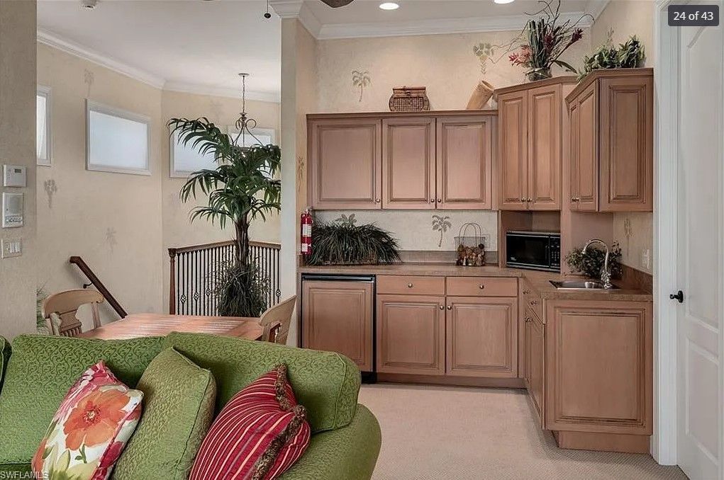 Living room with green sofa, kitchen with wood cabinets, dining table, and large indoor tree.