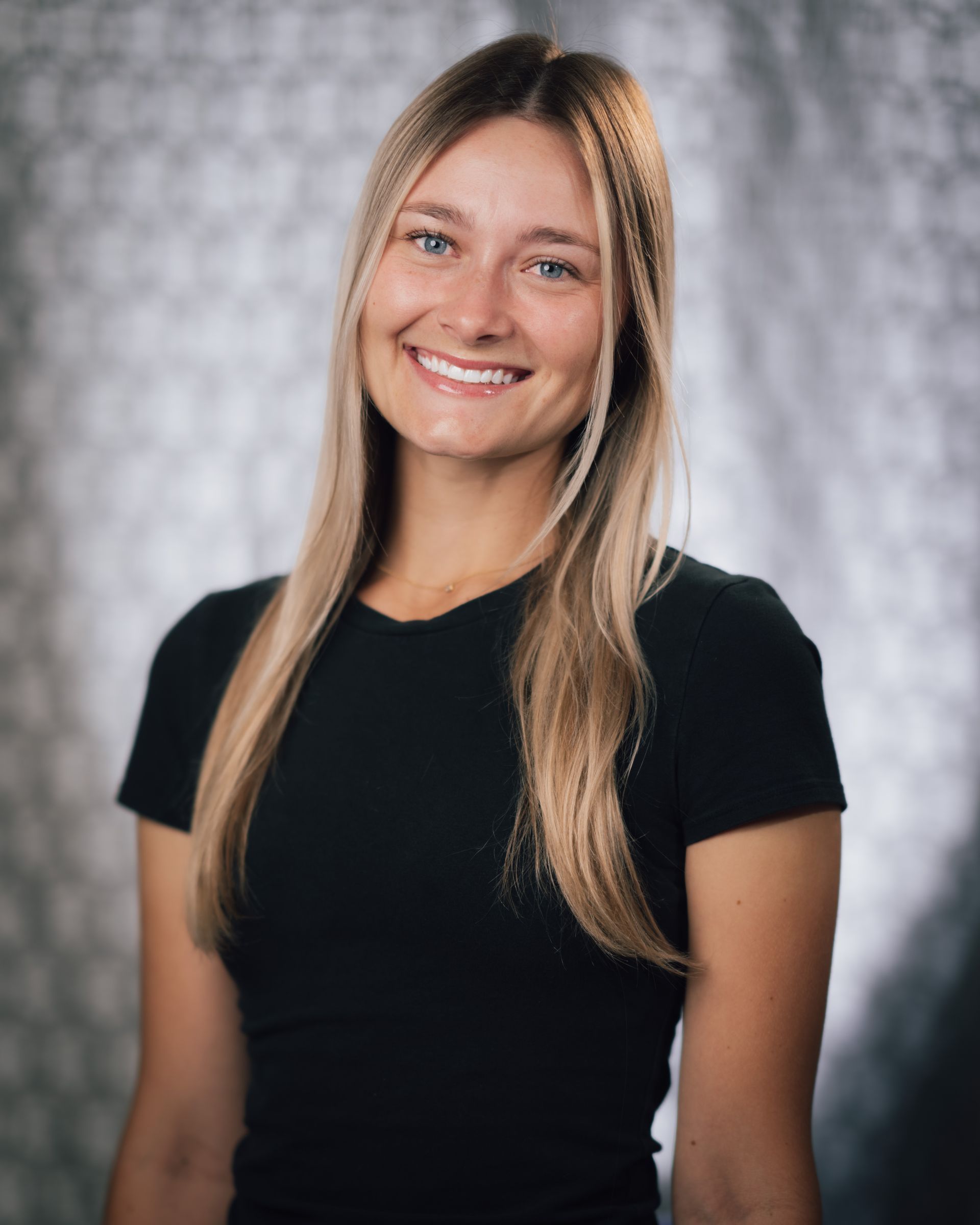 The woman is wearing a black shirt and smiling for the camera.