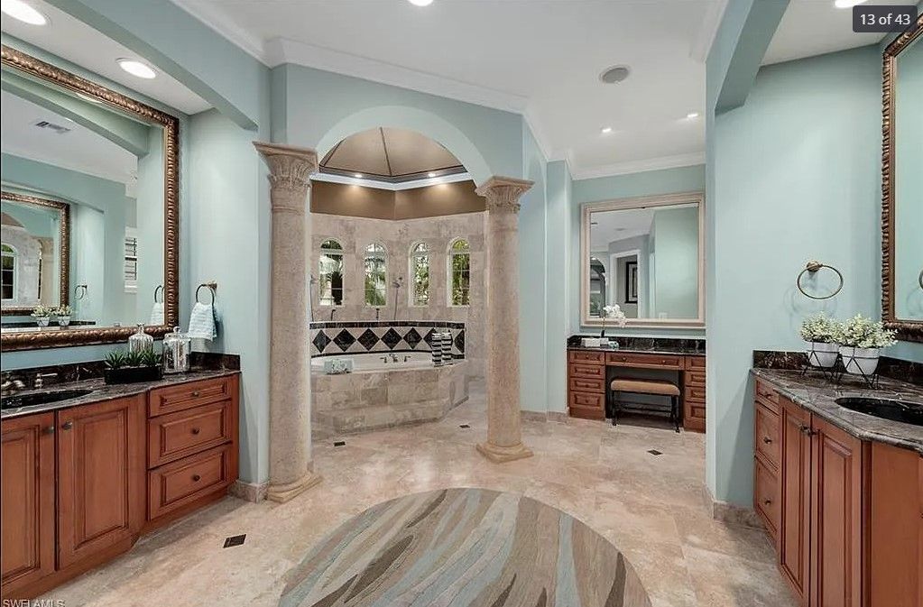 Elegant bathroom with light blue walls, marble flooring, and wood cabinetry.