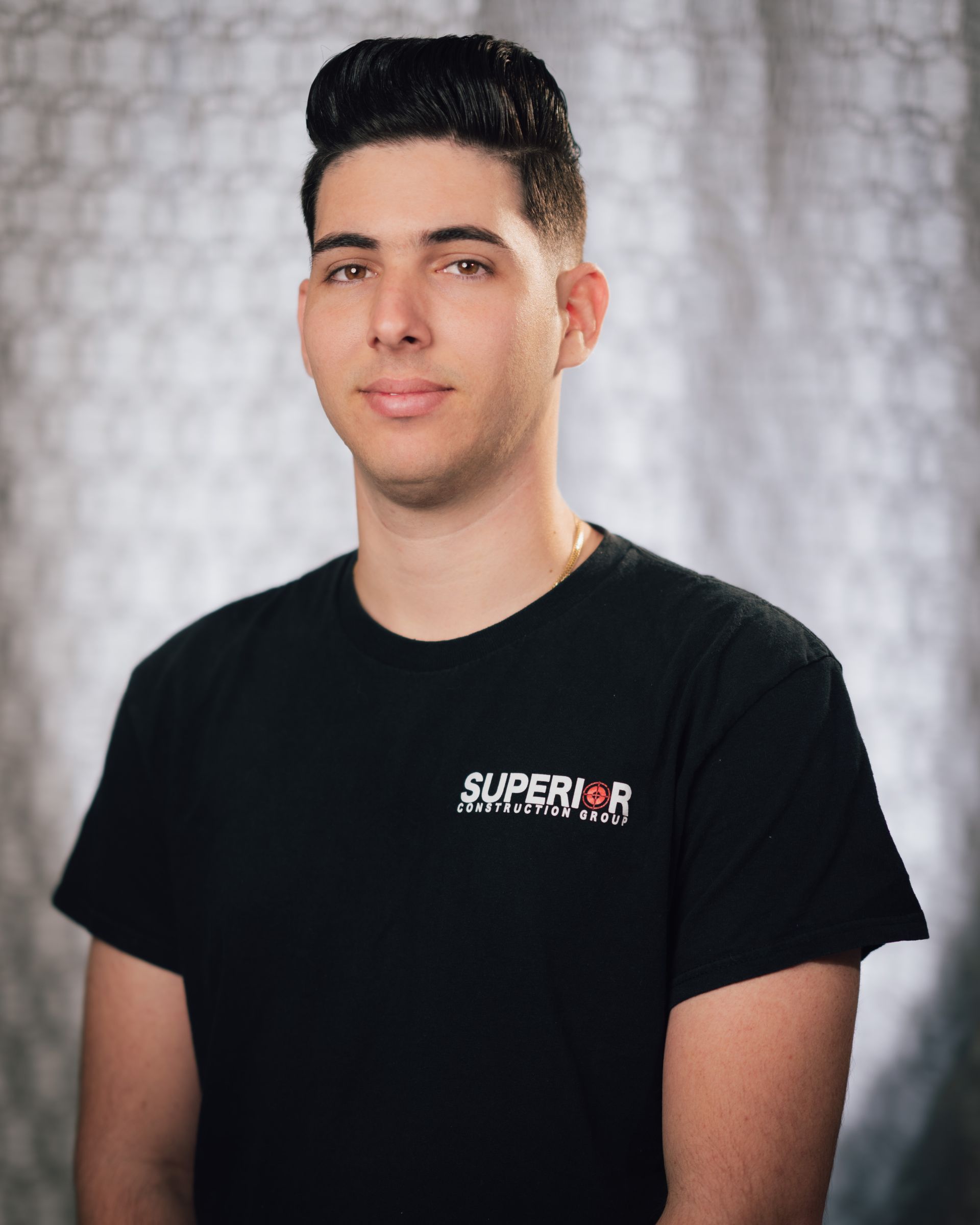 A young man wearing a black shirt with the word superior on it