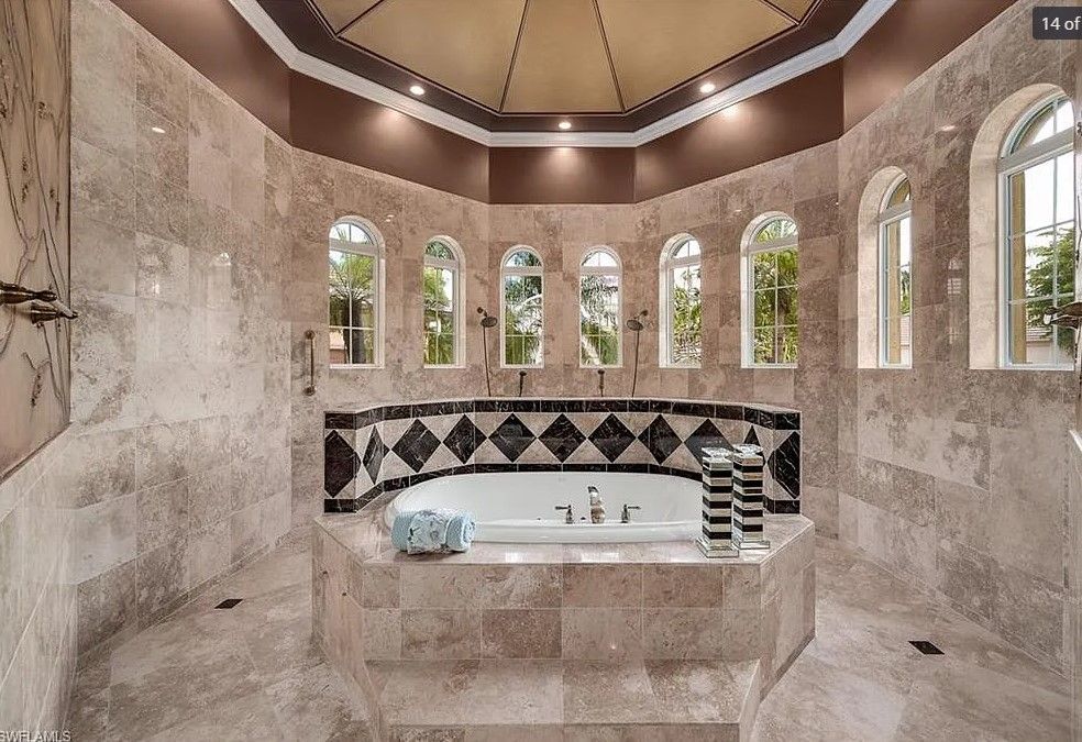 Luxury bathroom with marble walls, arched windows, and a sunken jacuzzi.