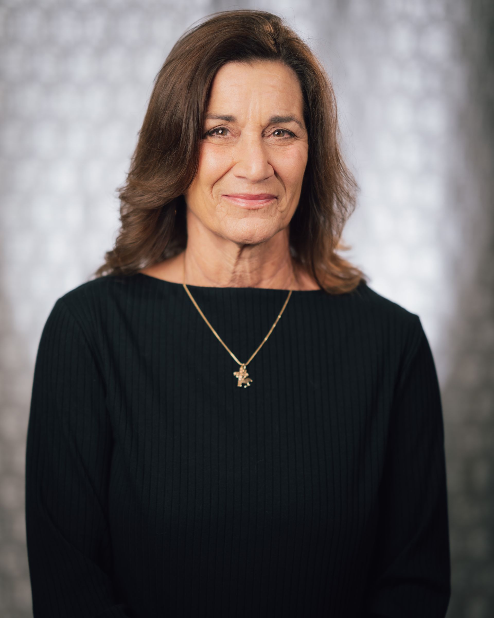 A woman wearing a black dress and a gold necklace with a star pendant.