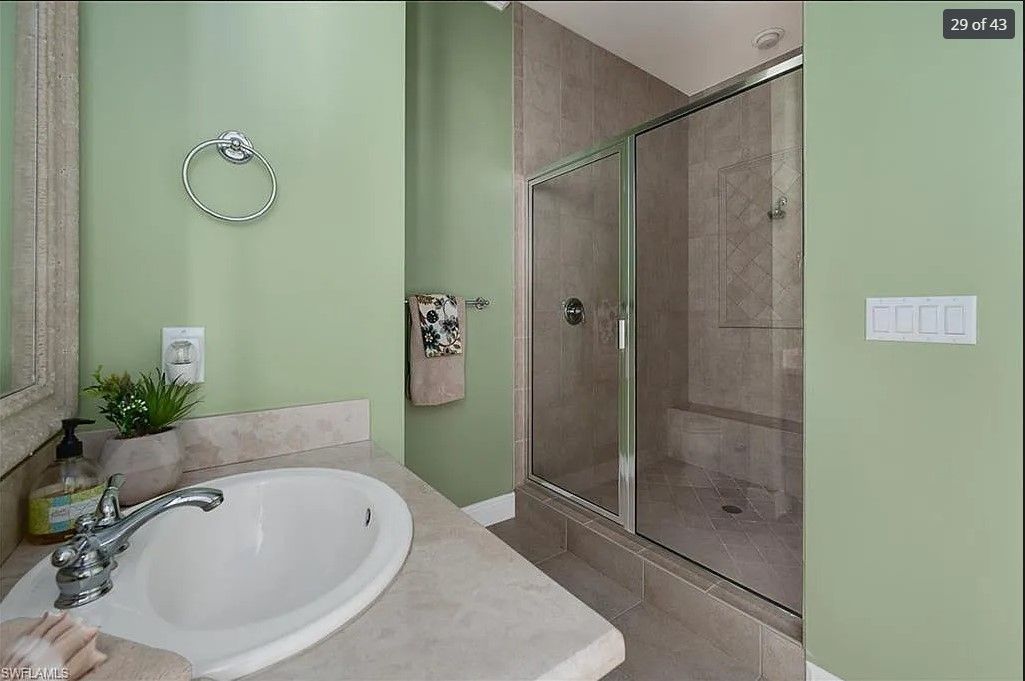 Bathroom with a white sink, glass shower, and green walls.