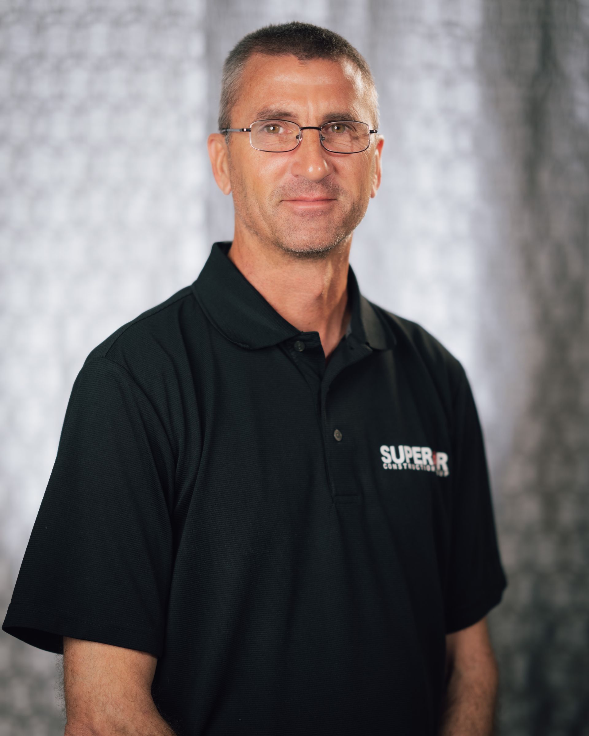 A man wearing glasses and a black shirt that says superior