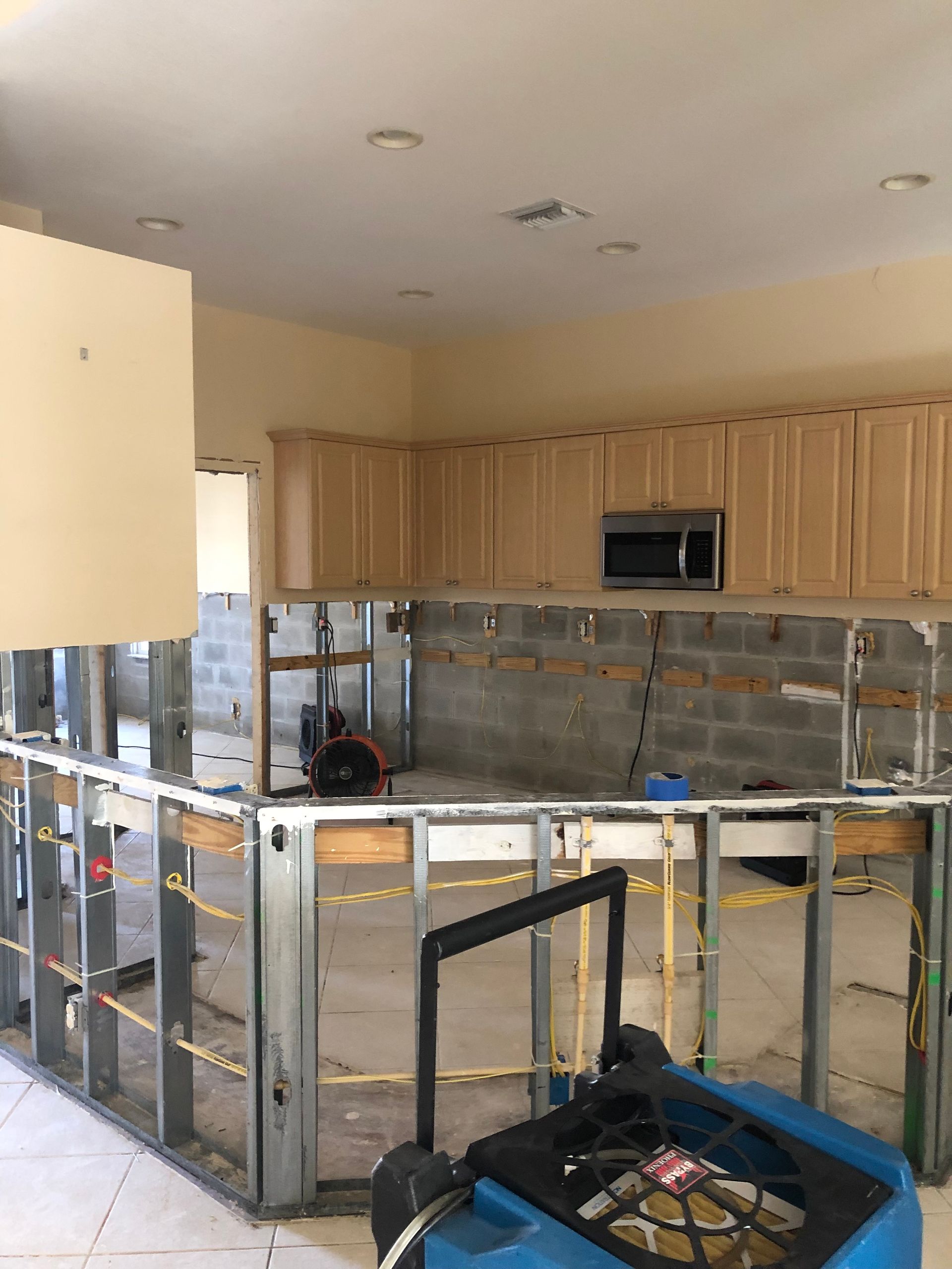 A kitchen under construction with wooden cabinets and a microwave.