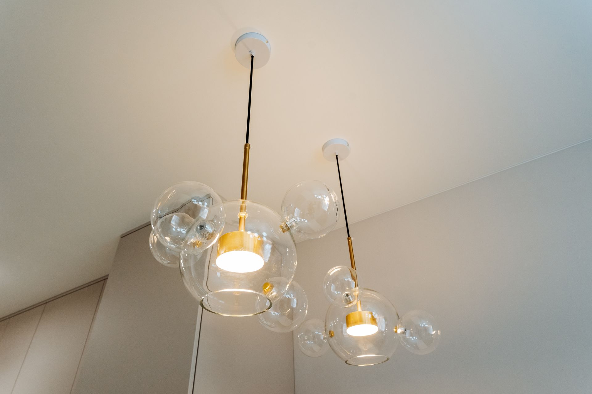 Two modern glass pendant lights hanging from the ceiling in a bright room