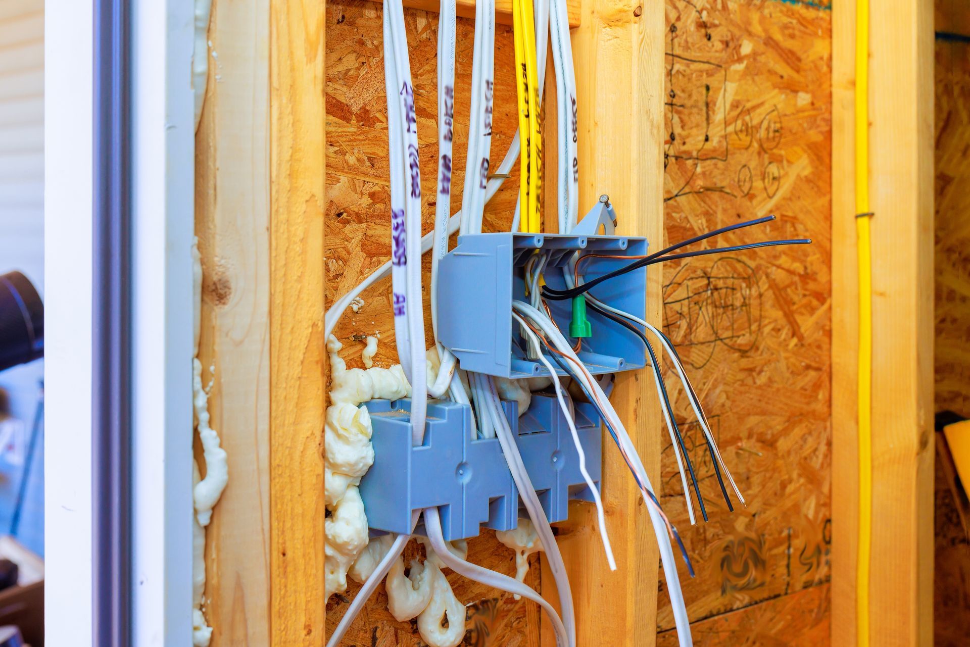 Electrical wiring in a wall outlet box inside a wood-framed construction wall.