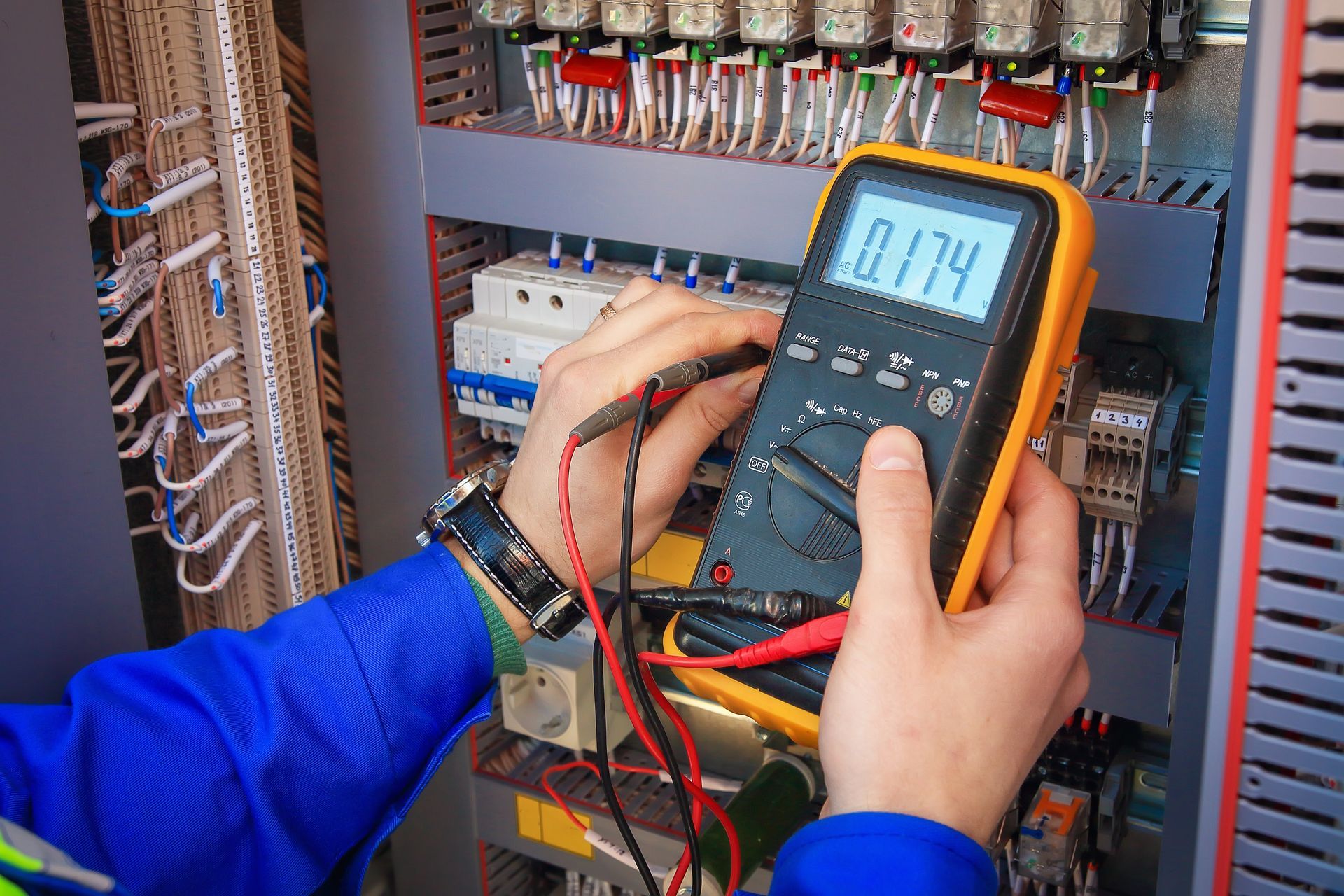Technician testing electrical panel with a digital multimeter in a server room