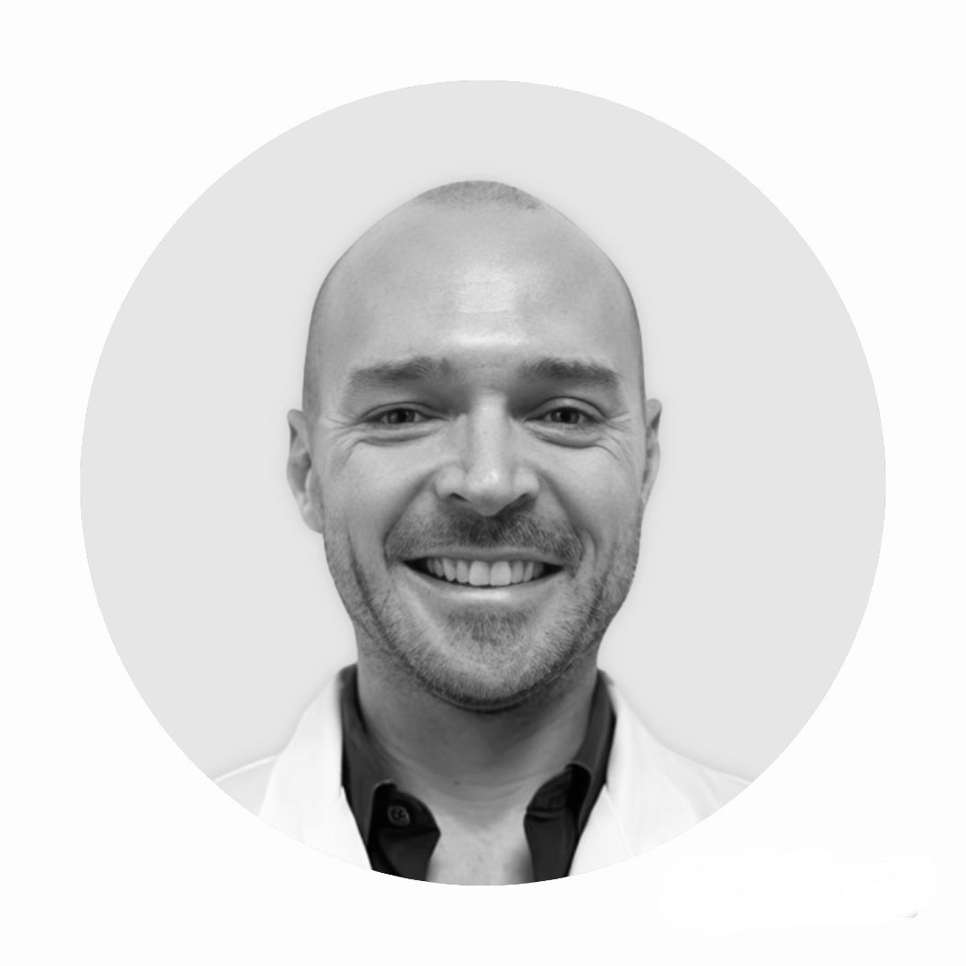 Un homme en blouse de laboratoire sourit sur une photo en noir et blanc.