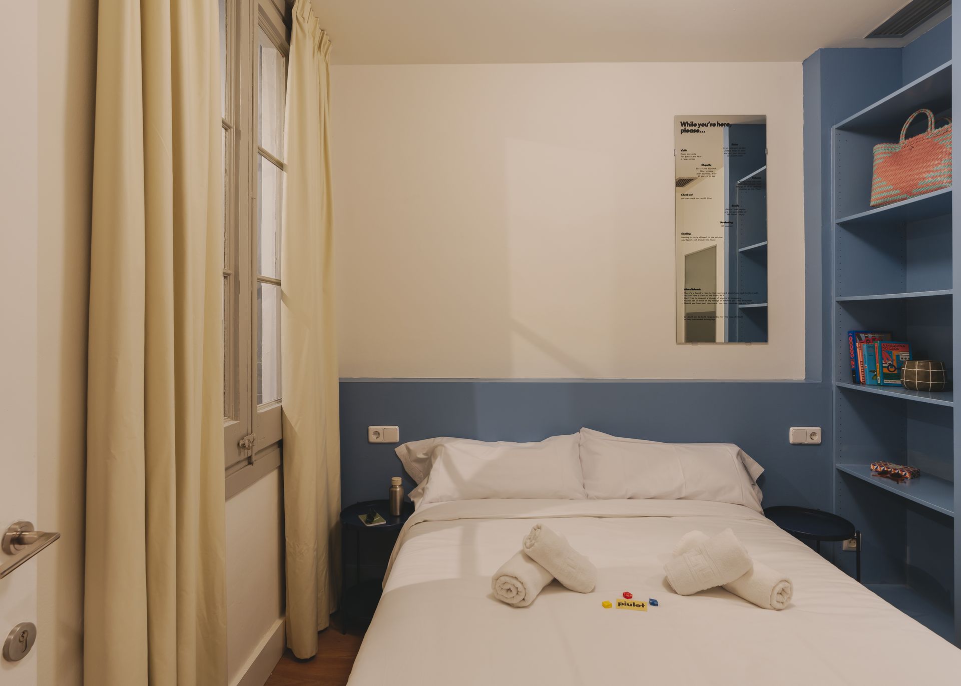 A bedroom with a bed , shelves and a window.