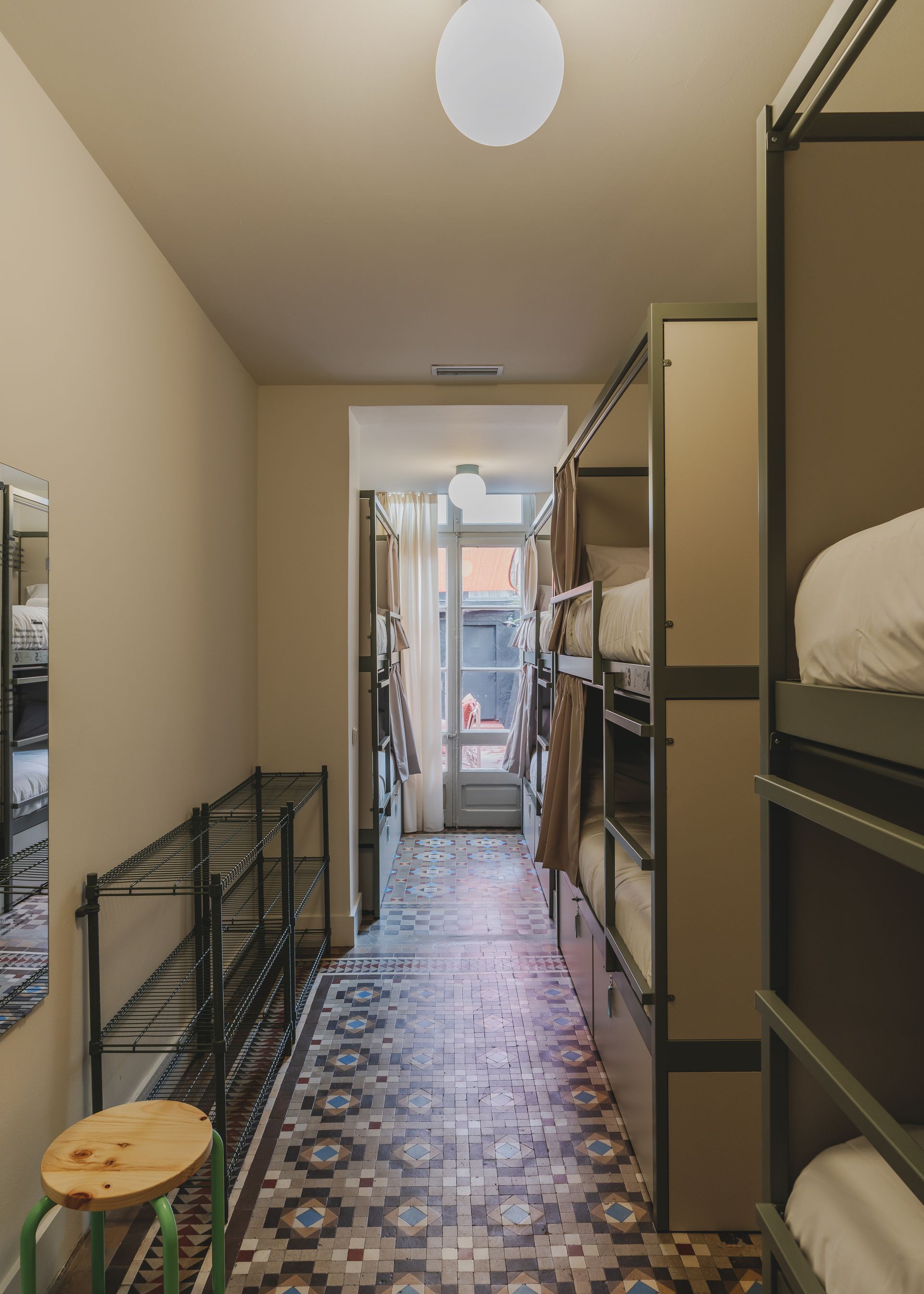 A long hallway with bunk beds and a green stool.