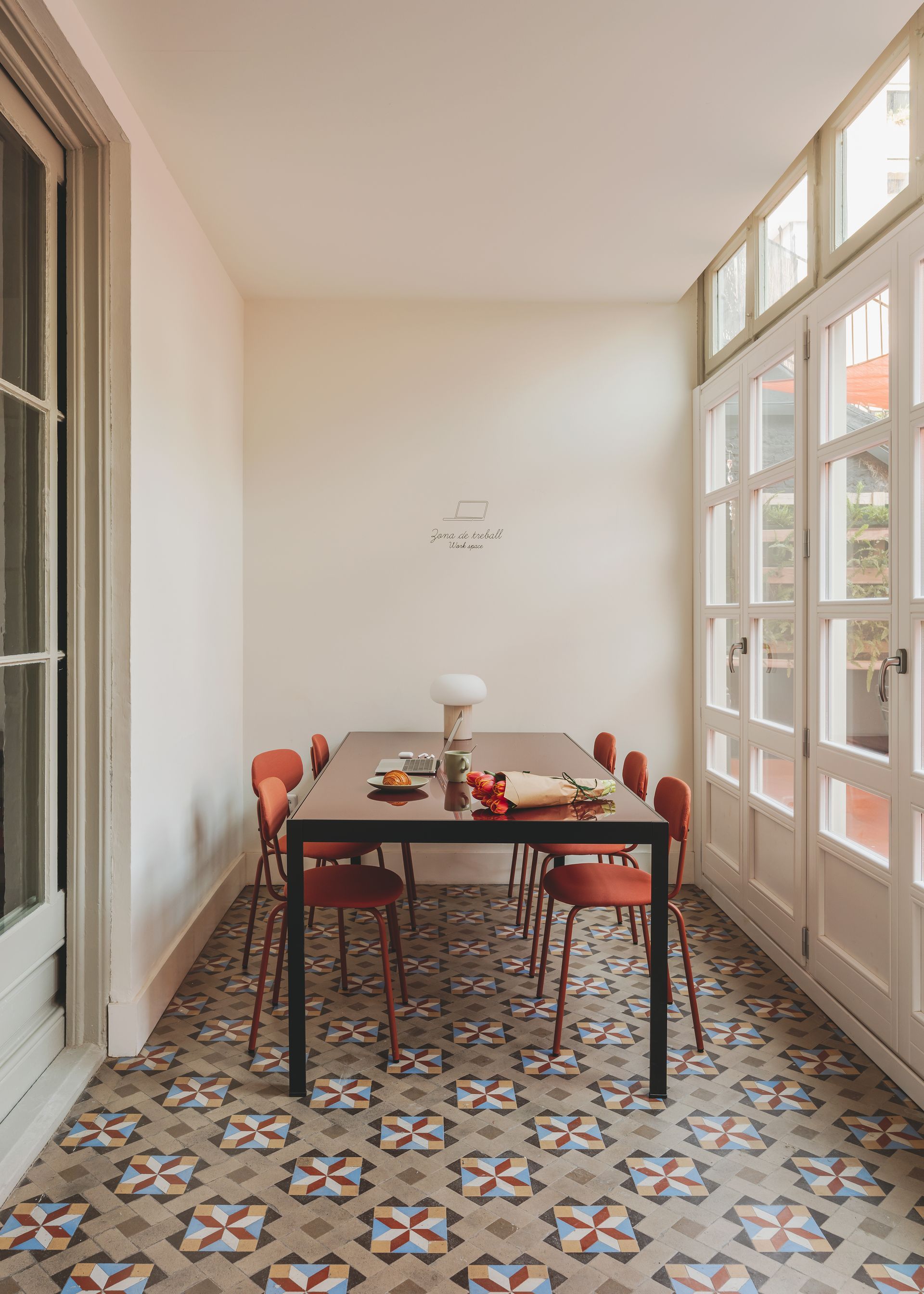 A dining room with a table and chairs and a tiled floor.