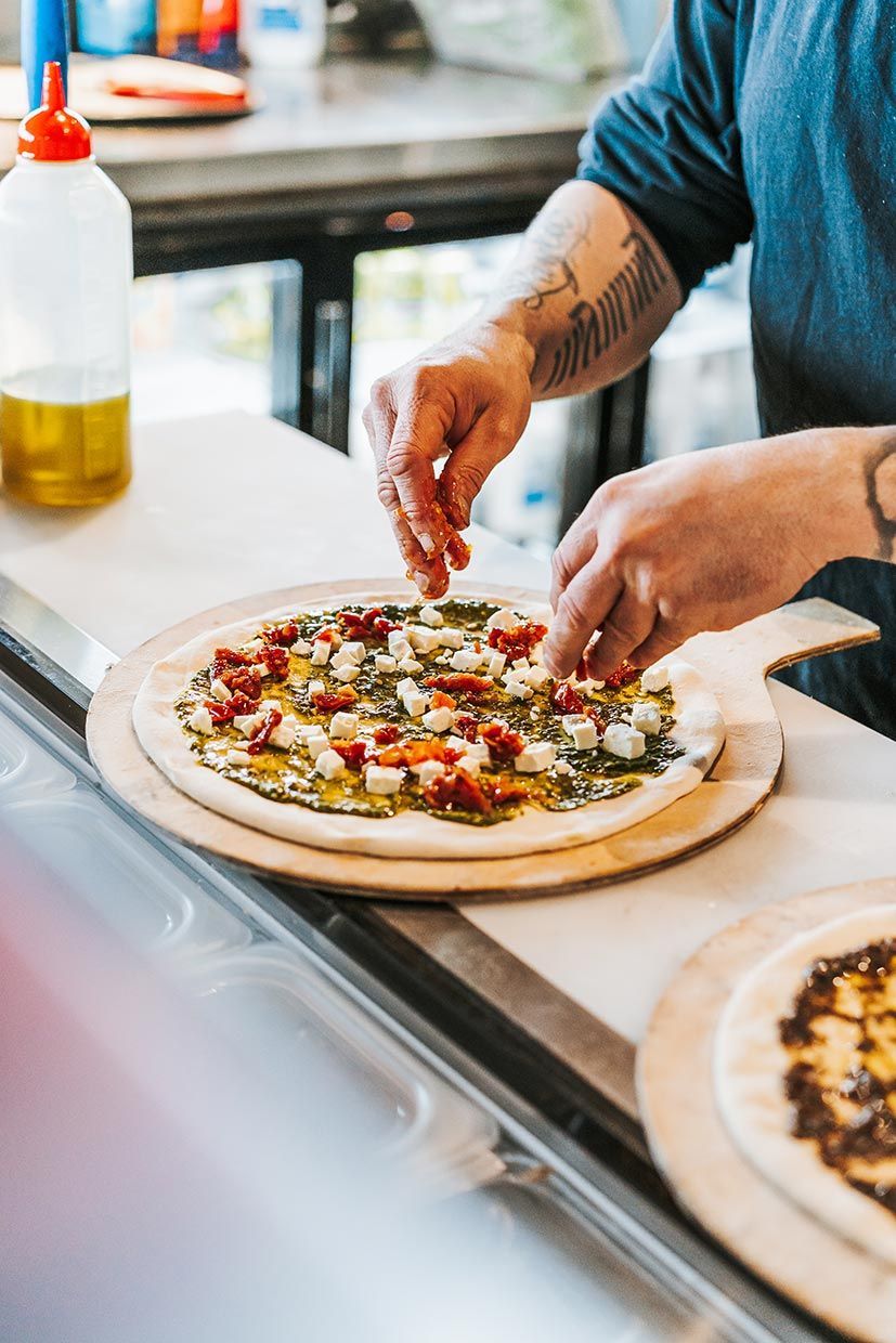 A Person is Making a Pizza on a Wooden Cutting Board — Fedeles East Gosford in East Gosford, NSW