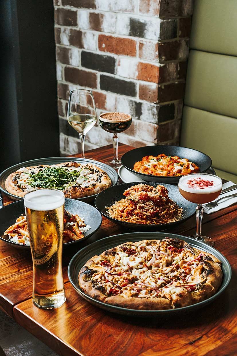 A Wooden Table Topped With Plates of Food and a Glass of Beer — Fedeles East Gosford in East Gosford, NSW