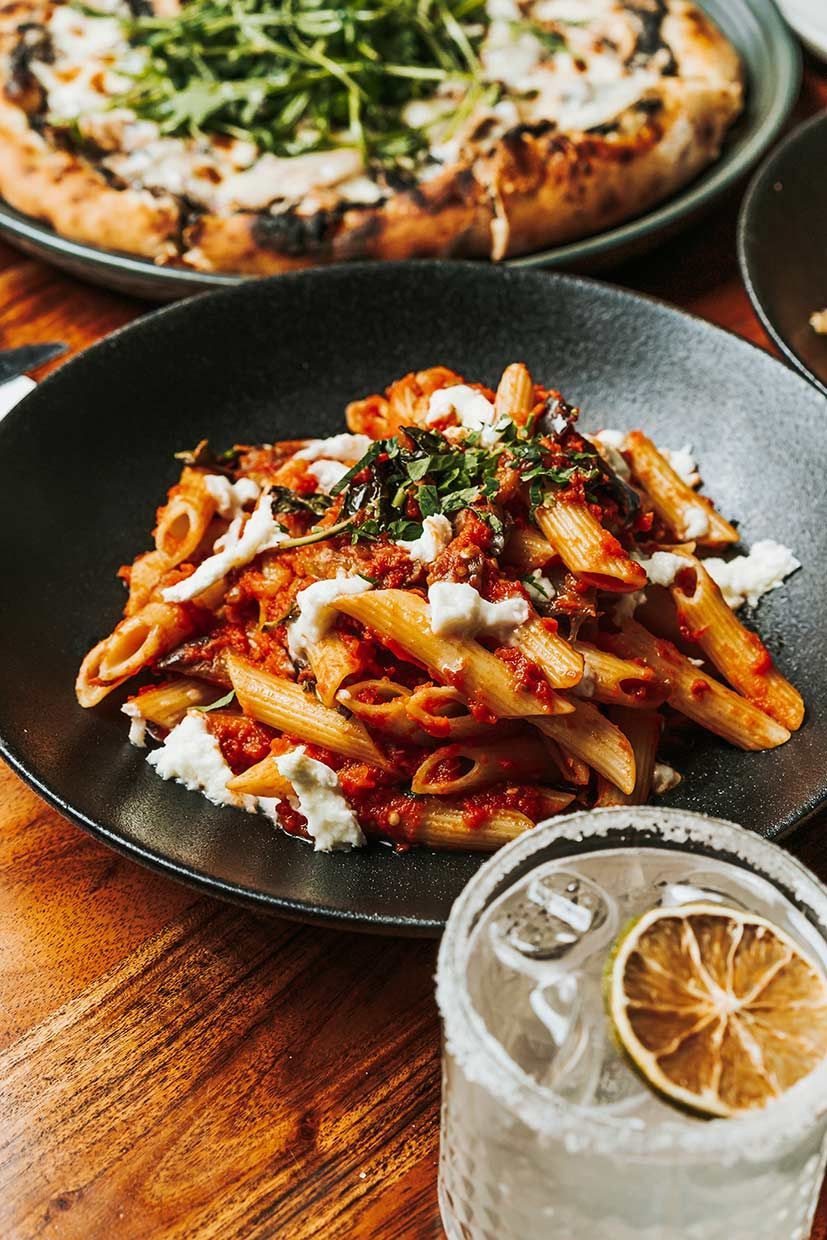A Plate of Pasta and a Glass of Water on a Wooden Table — Fedeles East Gosford in East Gosford, NSW