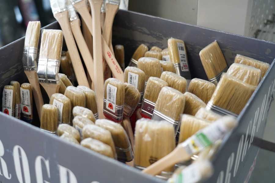 Barattoli di vernice aperti, pieni di vari colori vivaci, con un pennello al centro.
