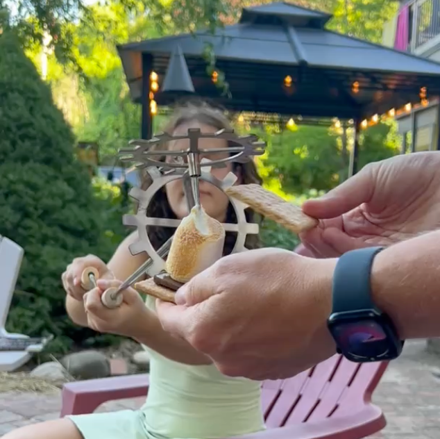 A woman is sitting in a chair eating a s'more