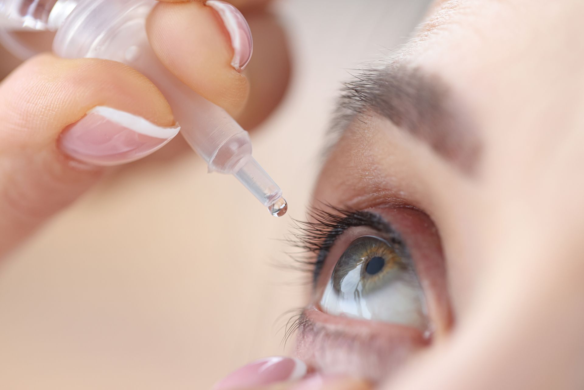 Person applying eye drops for dry eye relief.