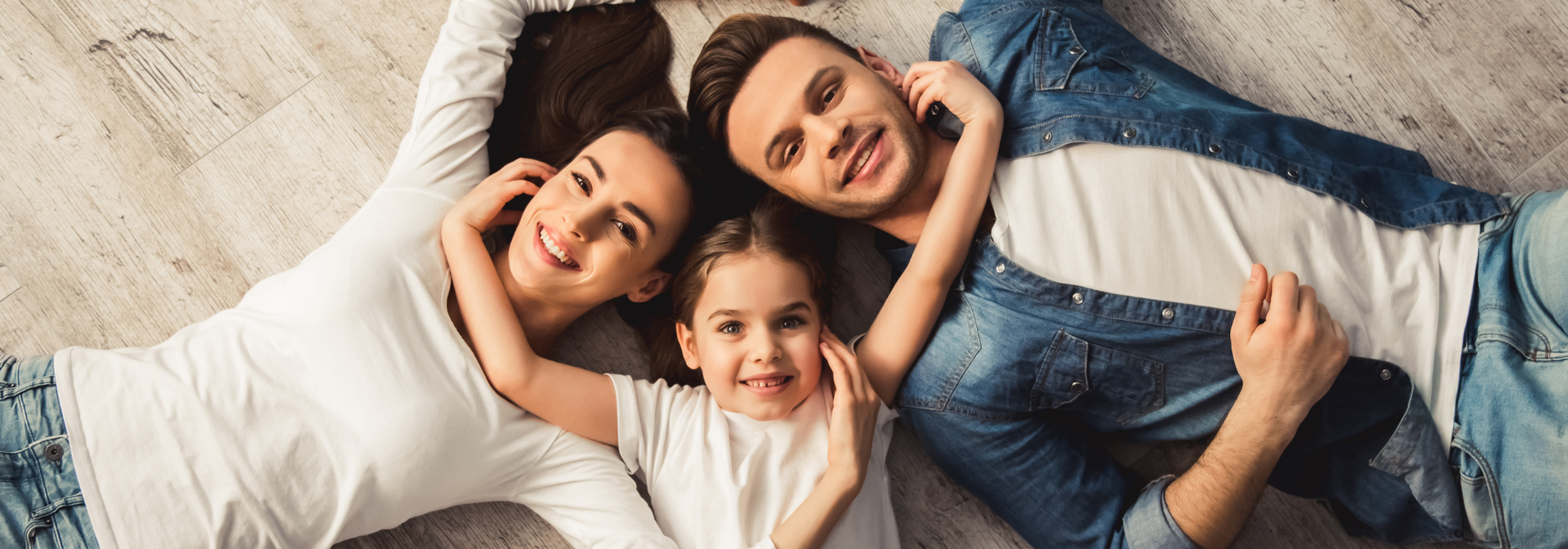 Three people lying on a couch, smiling and hugging each other
